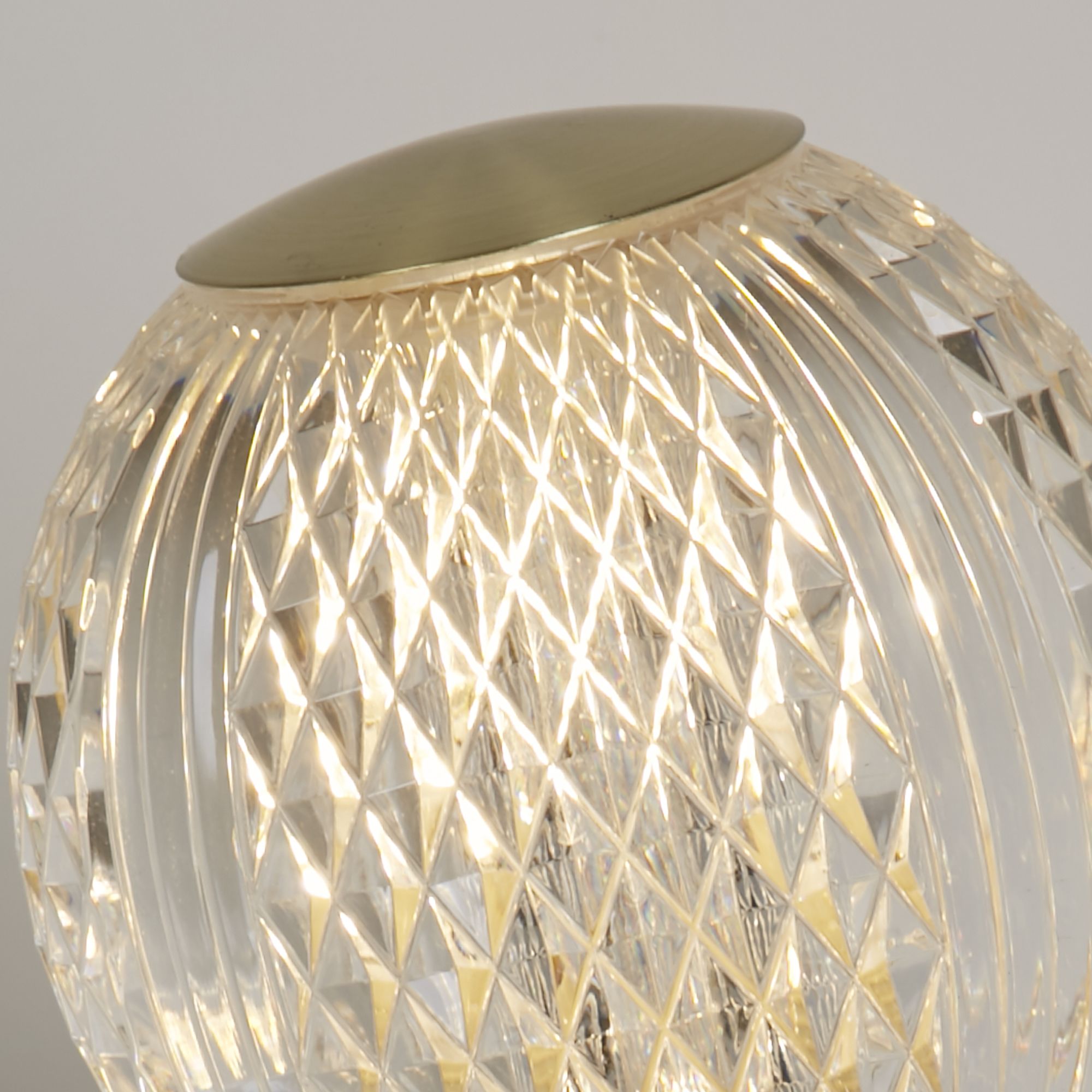Close up of the Allure table lamp's etched acrylic globe, showing the diamond cut texture lit from within