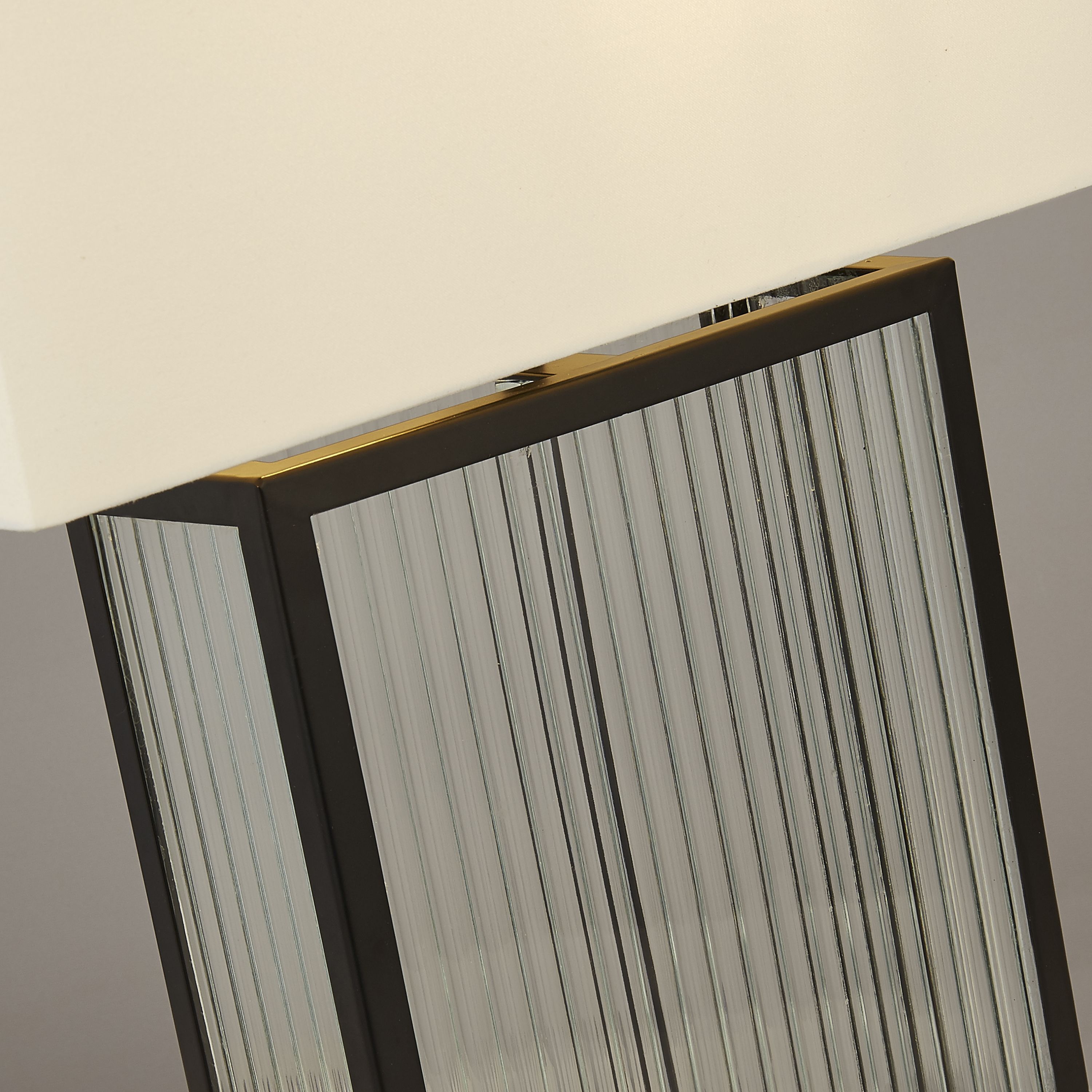Close up of the Clarendon table lamp's top corner, showing the fluted glass texture inside the black metal frame with a brass coloured trim detail