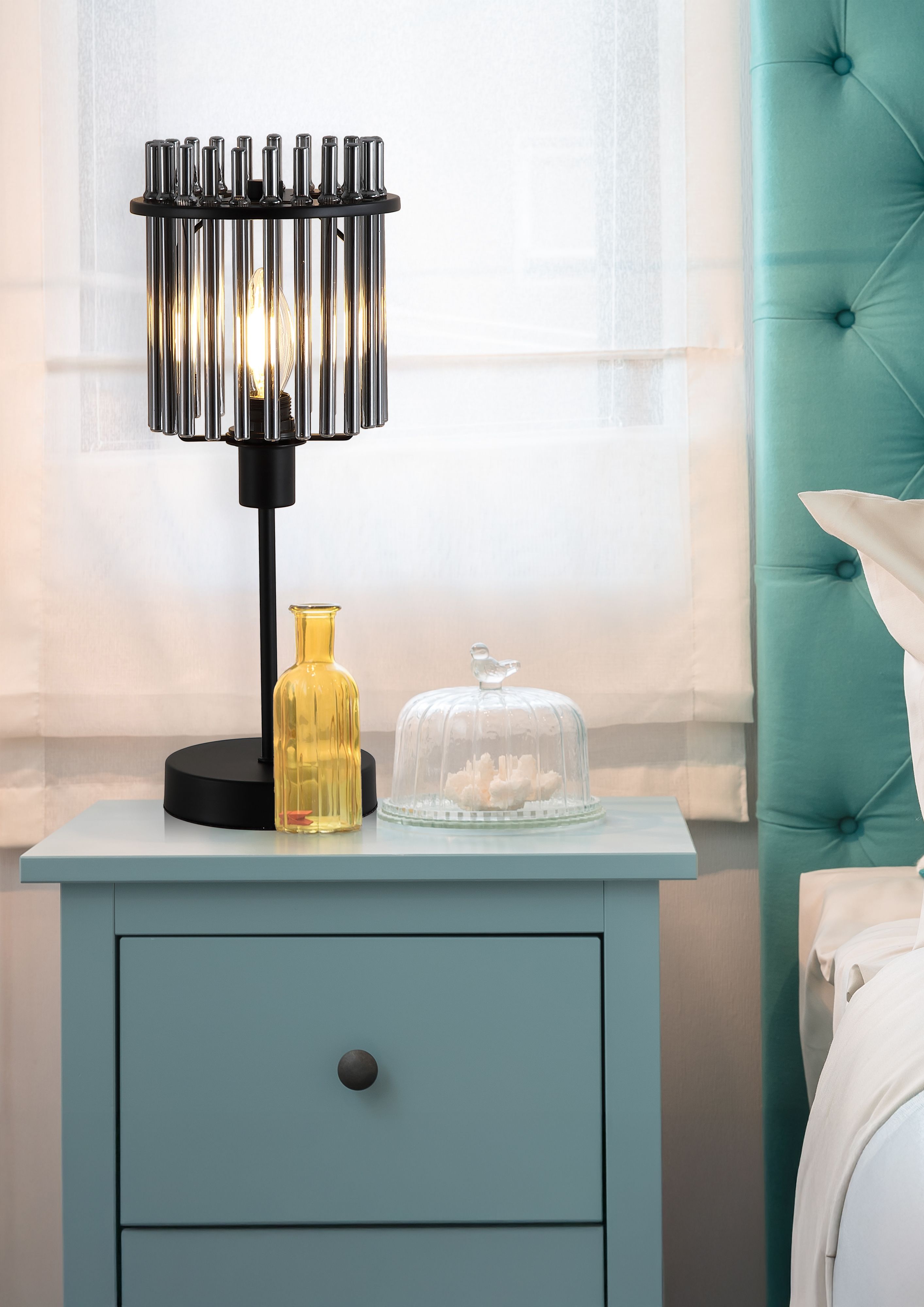 Searchlight Swizzle matt black table lamp styled on a blue bedside table next to an amber glass vase and glass cloche
