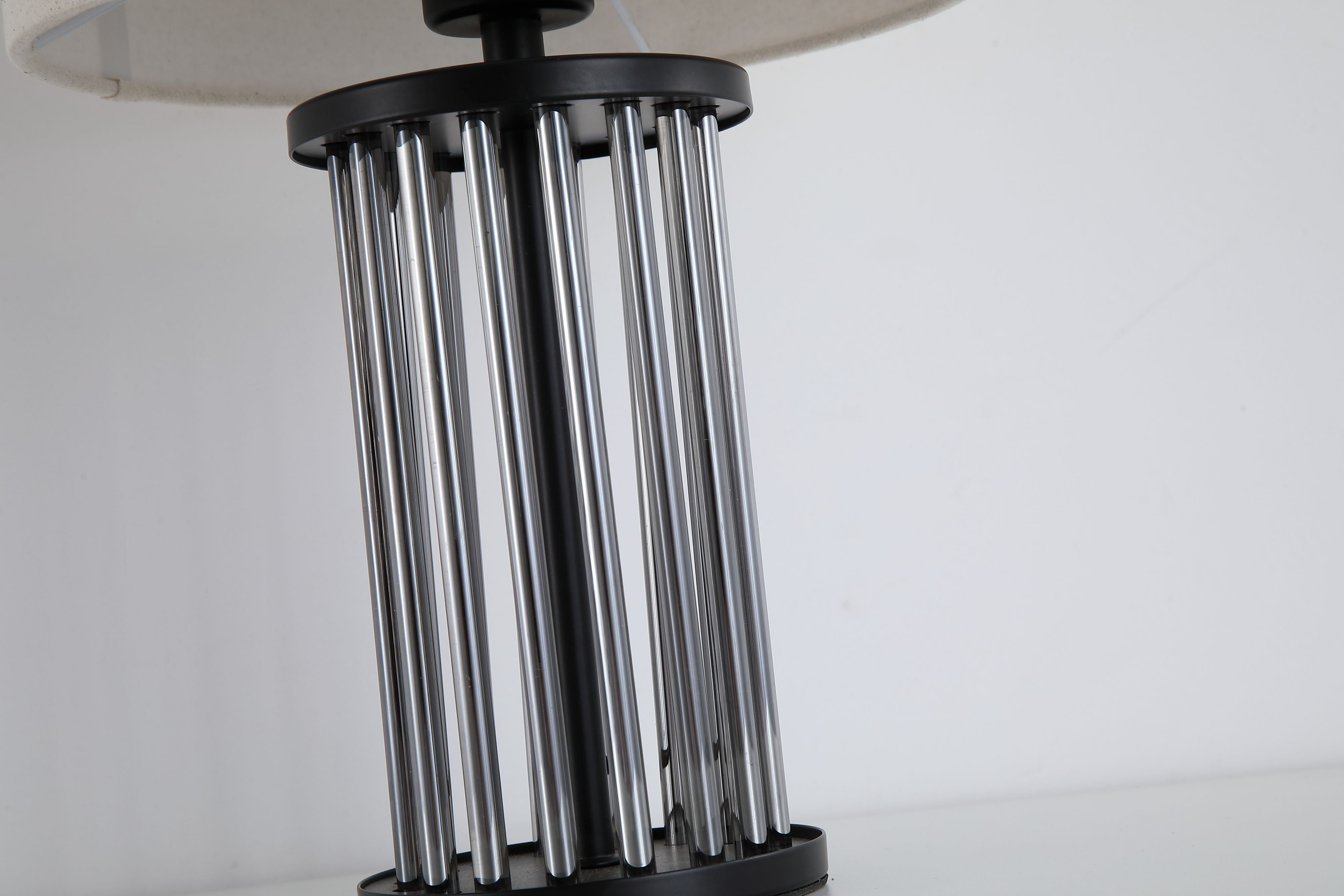 Close up of the Swizzle table lamp matt black rod base, showing the smoked glass rods set into the black finished top and base discs