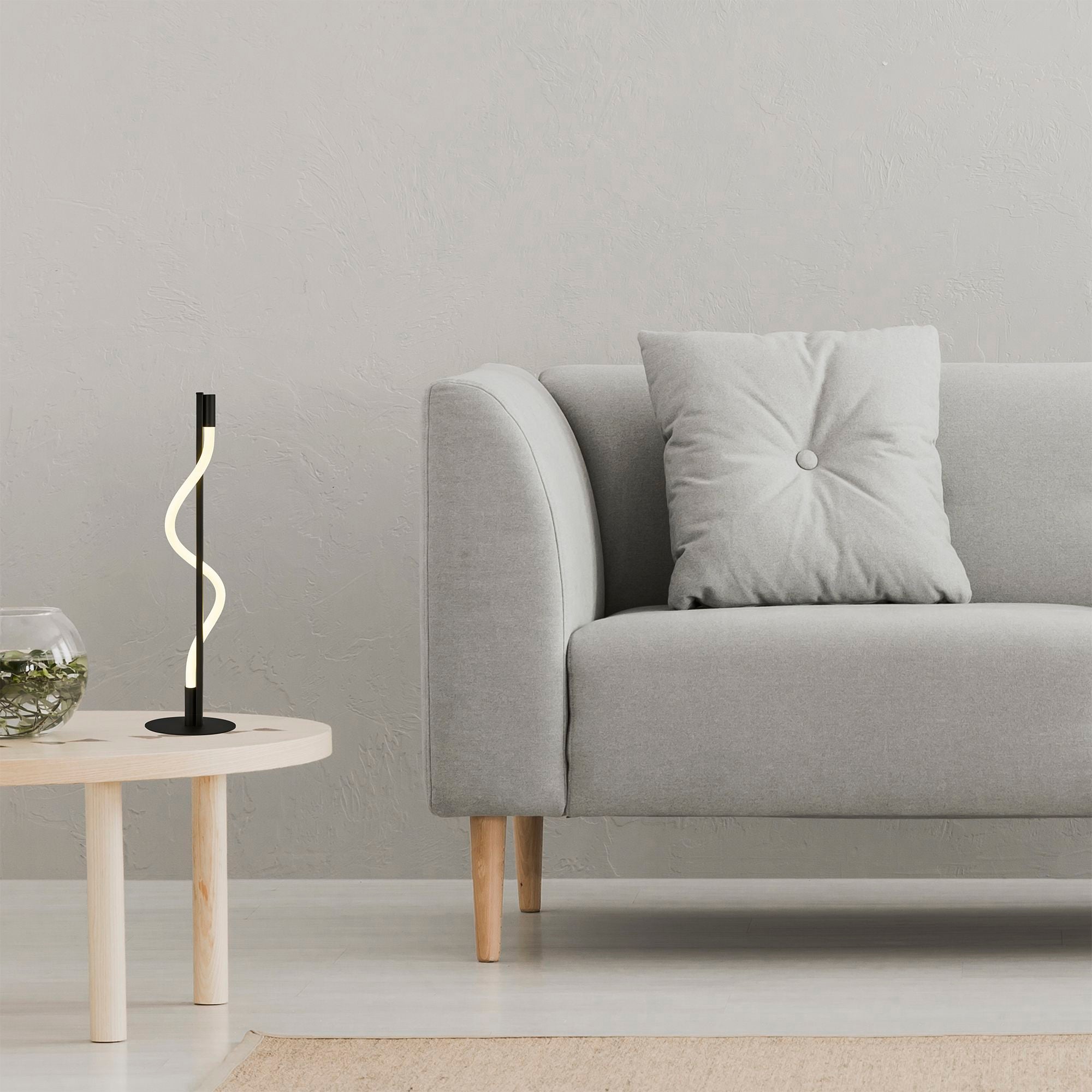Searchlight Serpent table lamp styled on a round wood side table beside a grey fabric sofa, with a glass planter and a light rug