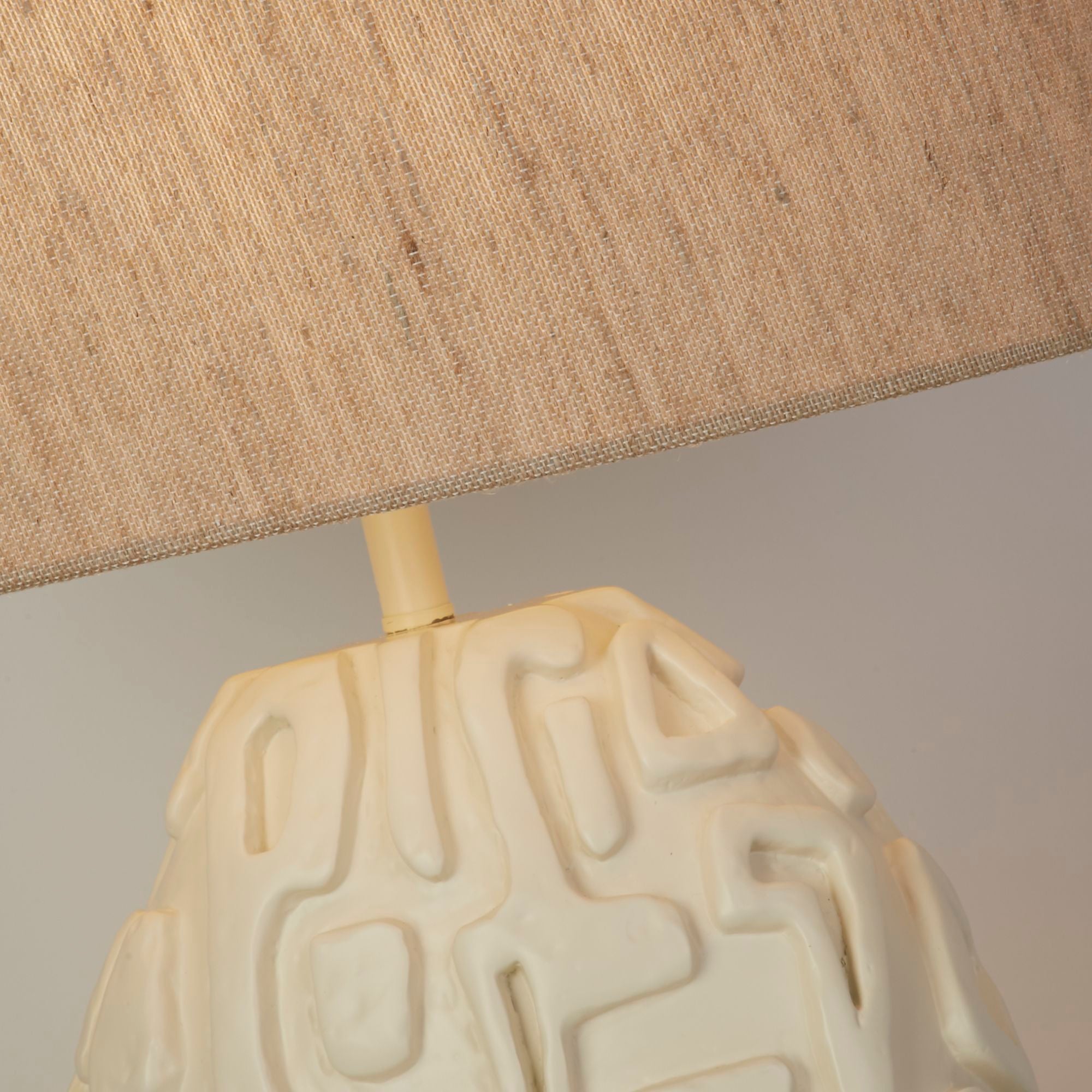 Close up of the Adelaide table lamp oatmeal linen shade fabric and the top of the carved cream resin base