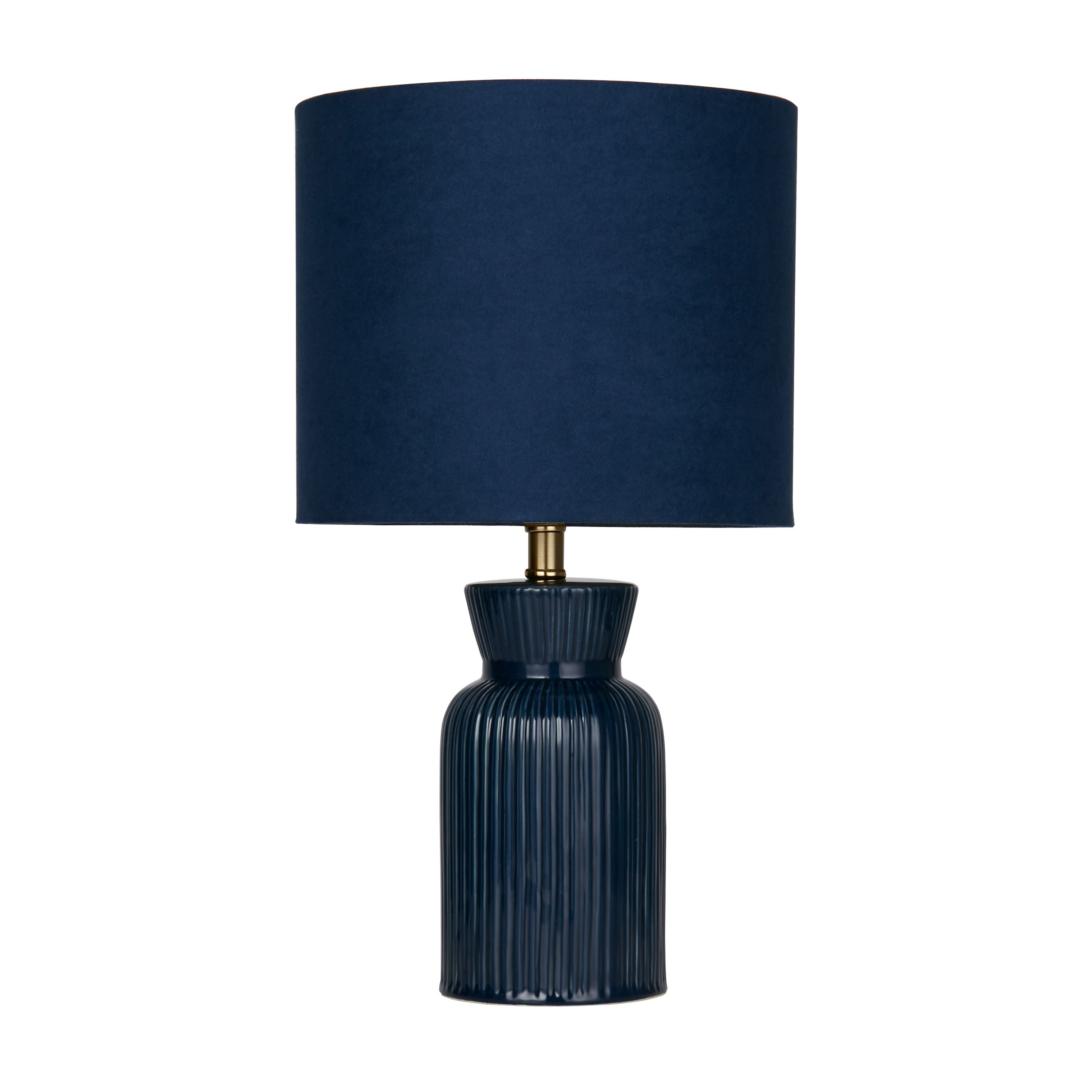 Navy ceramic table lamp on a plain white background, second angle showing the ribbed body and fluted neck