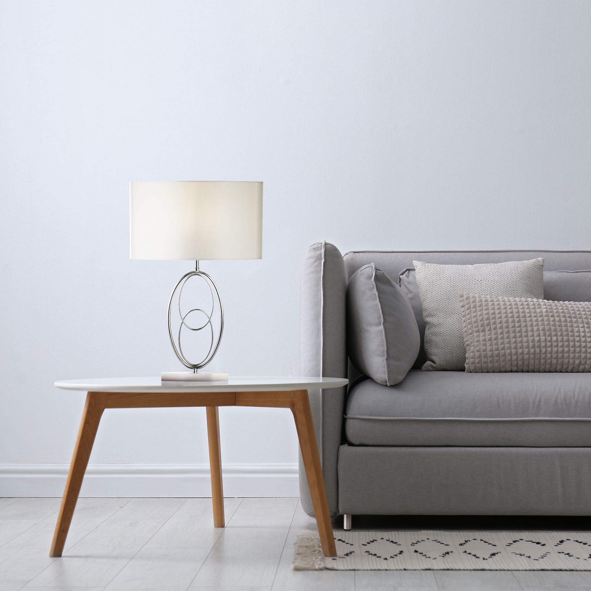 Loopy table lamp styled on a wooden coffee table beside a grey sofa