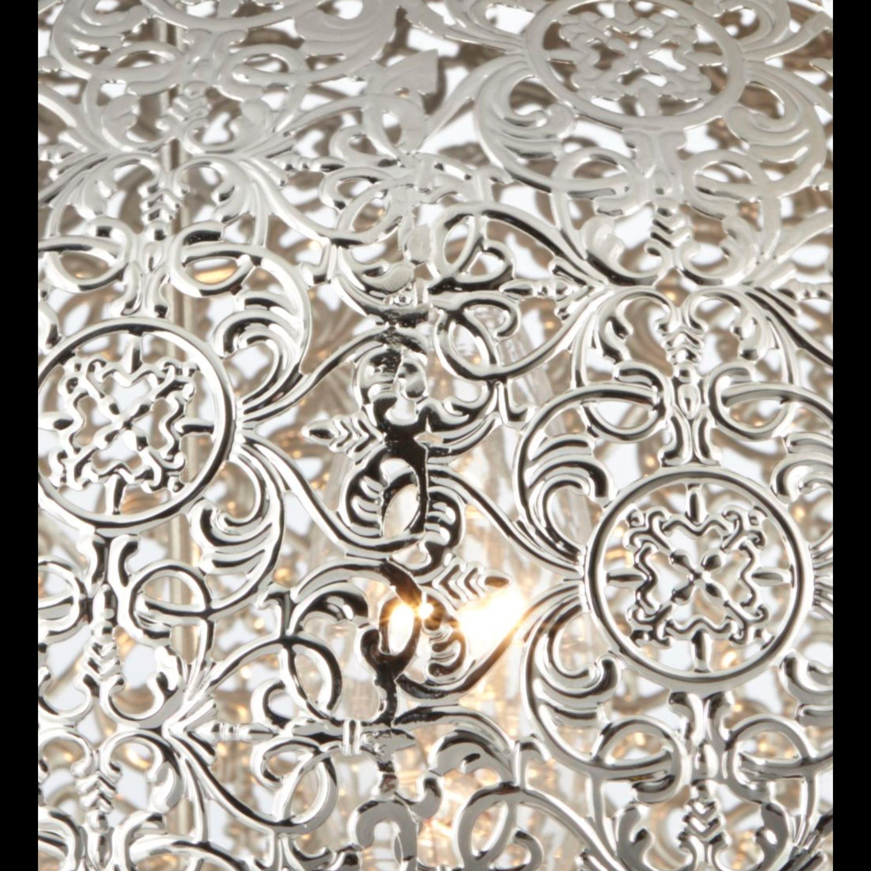 Close up of the laser cut pierced pattern on the Fretwork table lamp in nickel, lit from within