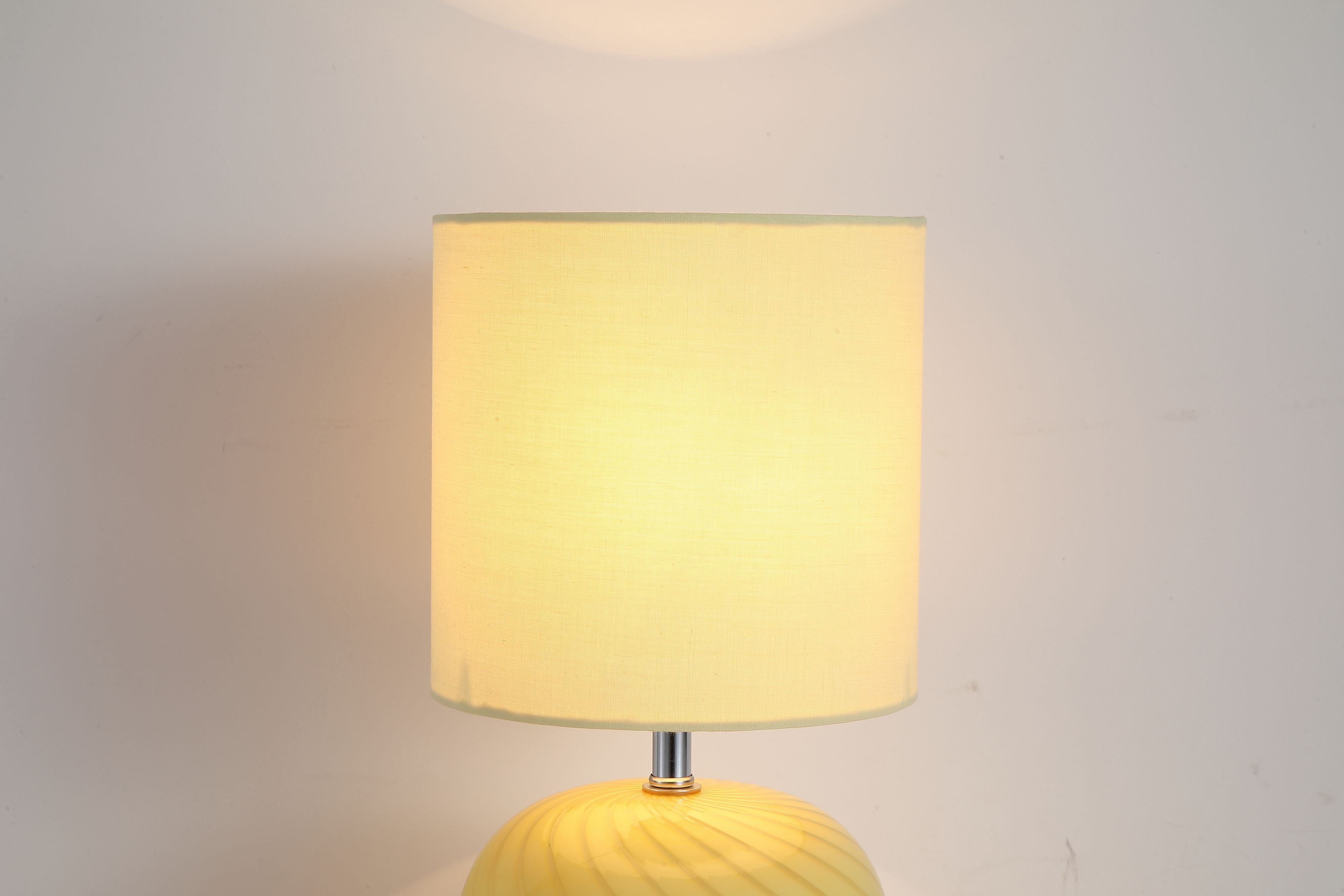 Extreme close up of the Fete lamp's yellow linen shade fabric and top edge, cropped tight against a plain grey background