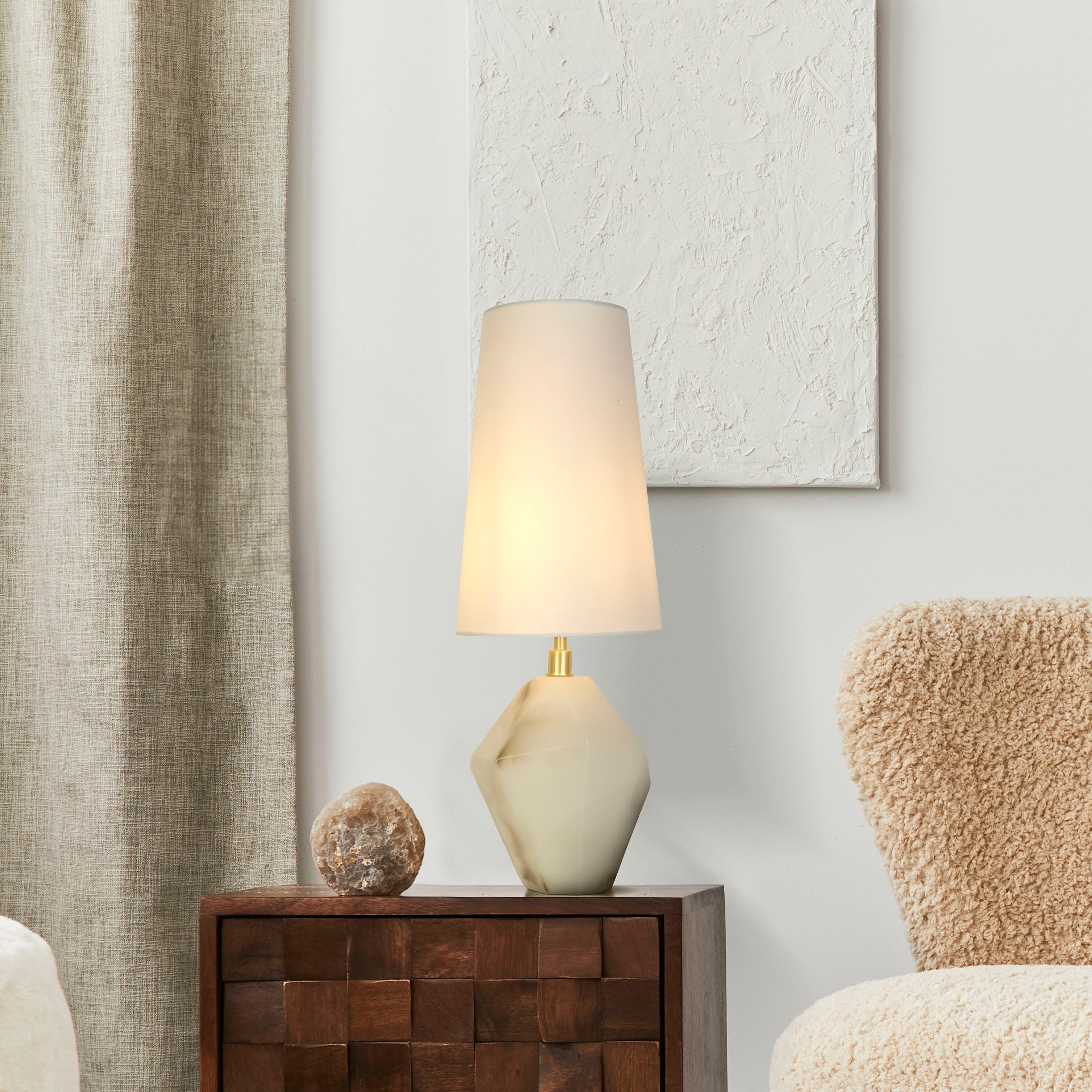 Apex white table lamp styled on a wooden cabinet next to a mineral stone ornament and curtain