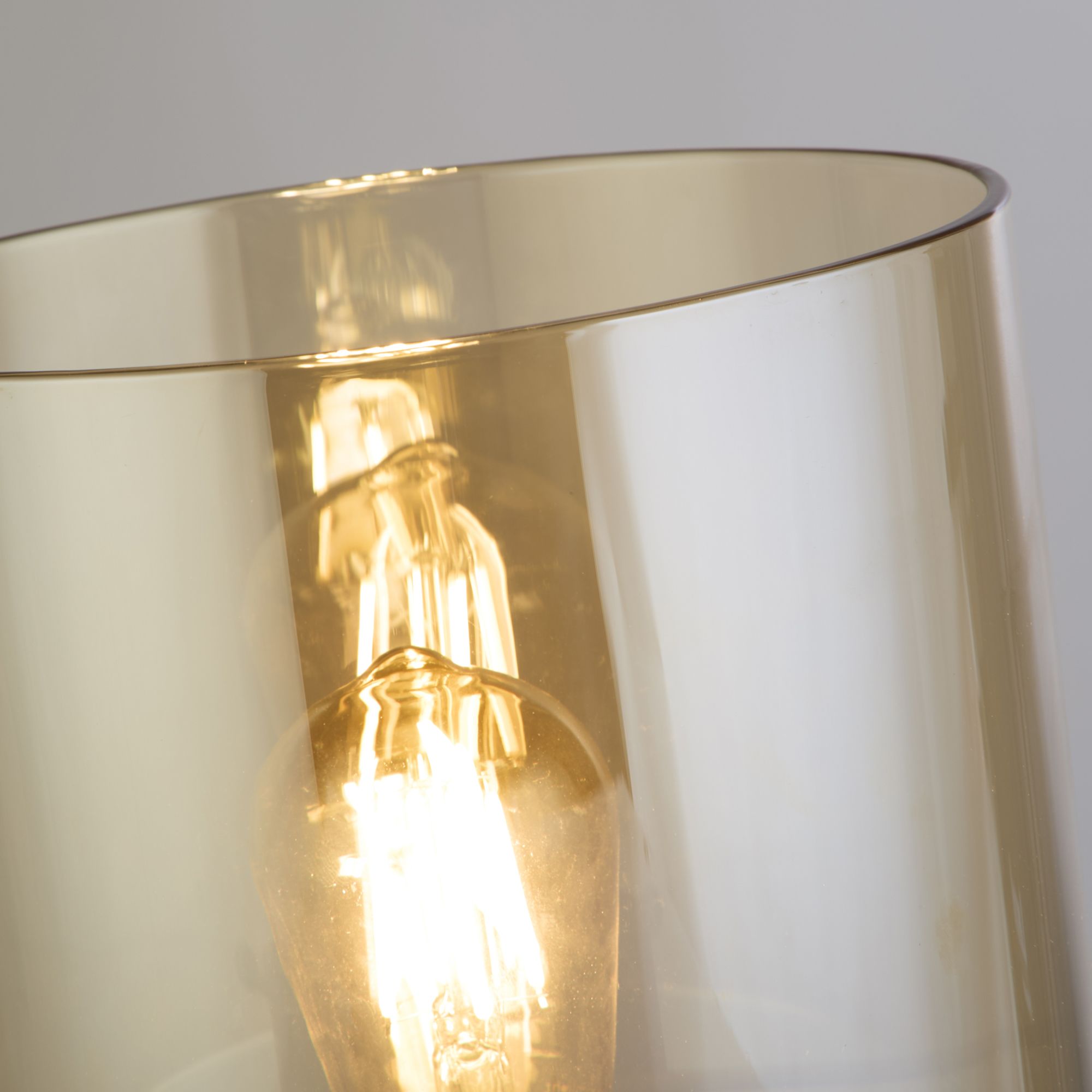 Close up of the lit bulb inside the amber glass shade on the Sweden 1 Light Table Lamp, showing the fade from amber to clear glass