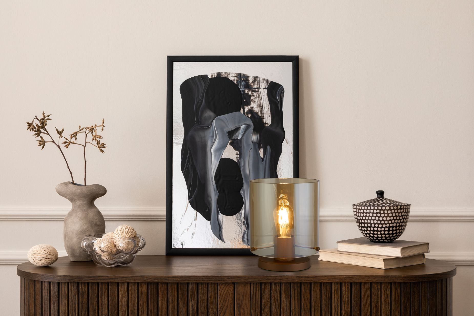 Searchlight Sweden 1 Light Table Lamp in mocha metal and amber glass styled on a wooden sideboard beside a framed abstract print and books