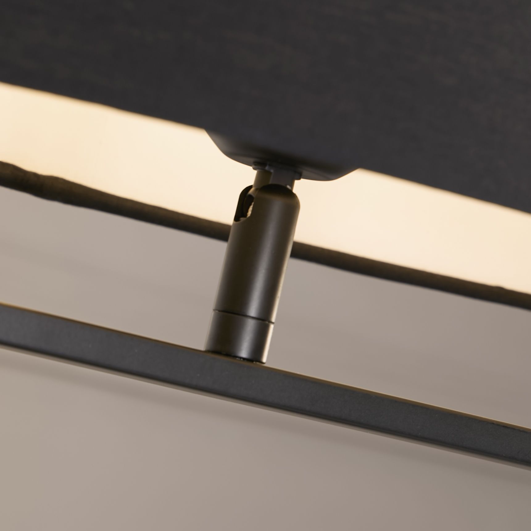 Close up of the Sleek table lamp's black finial and lamp holder where the shade meets the oval metal base.