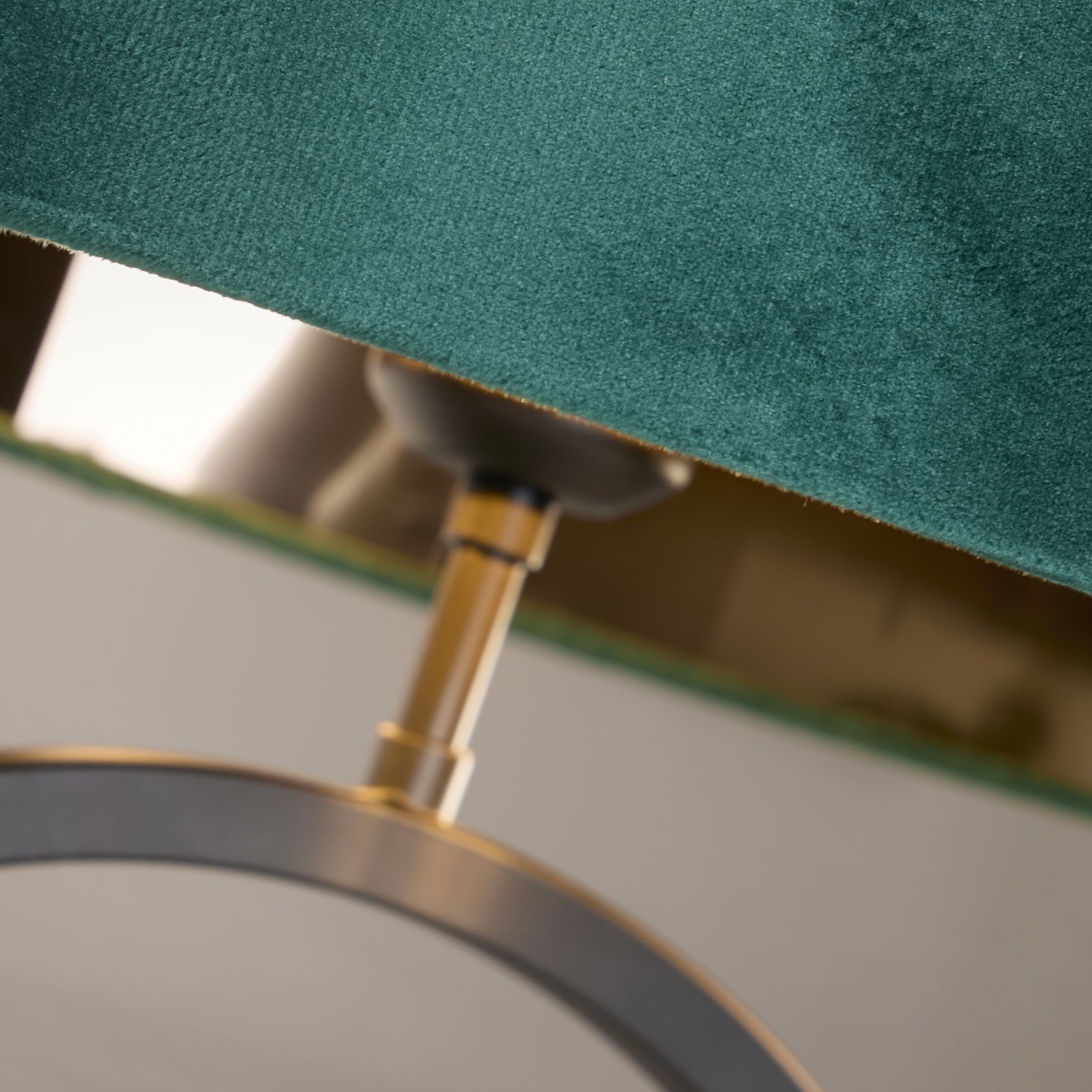 Close up of the brass coloured collar joint connecting the emerald velvet shade to the matt black ring base