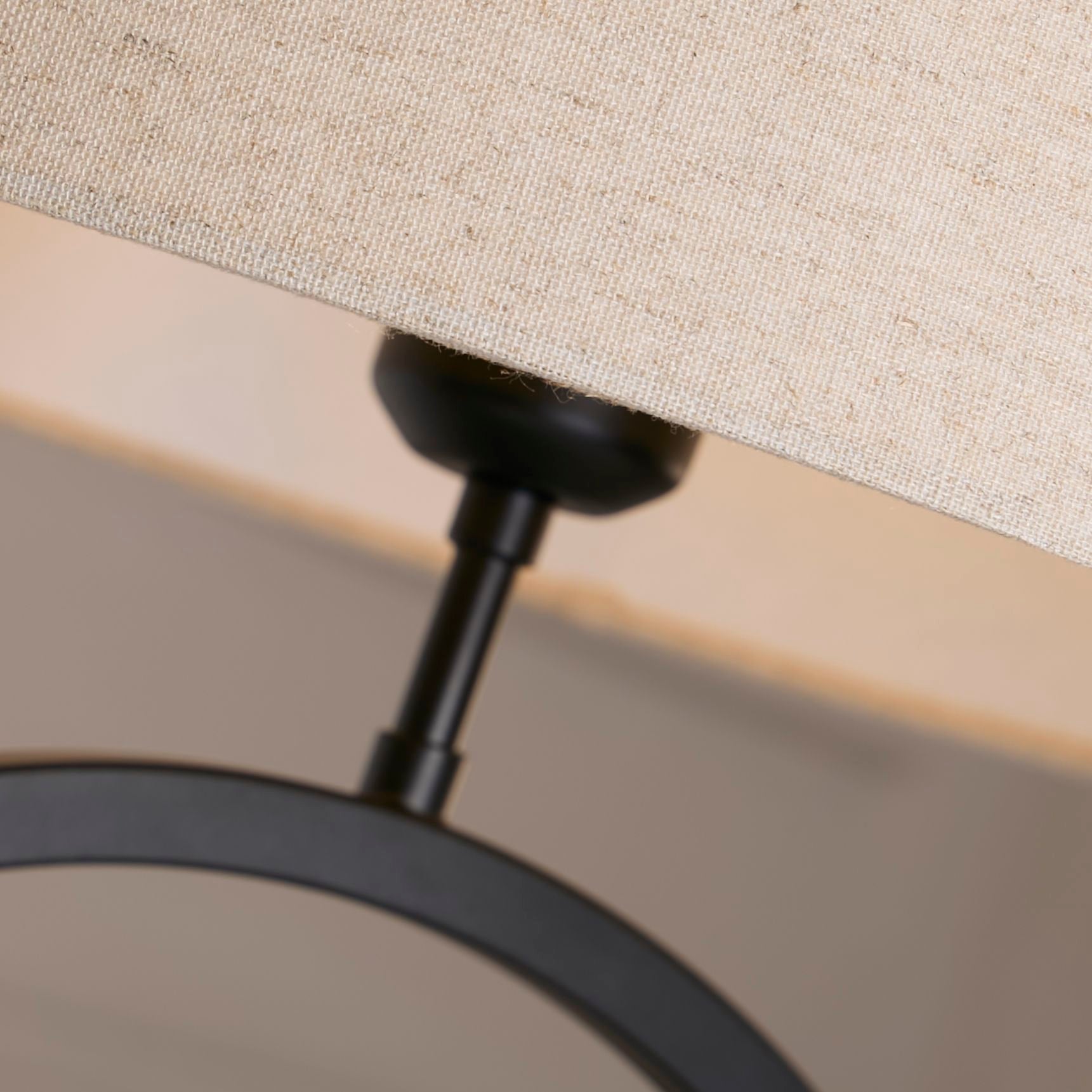 Close up of the black collar joint connecting the natural linen shade to the matt black ring base