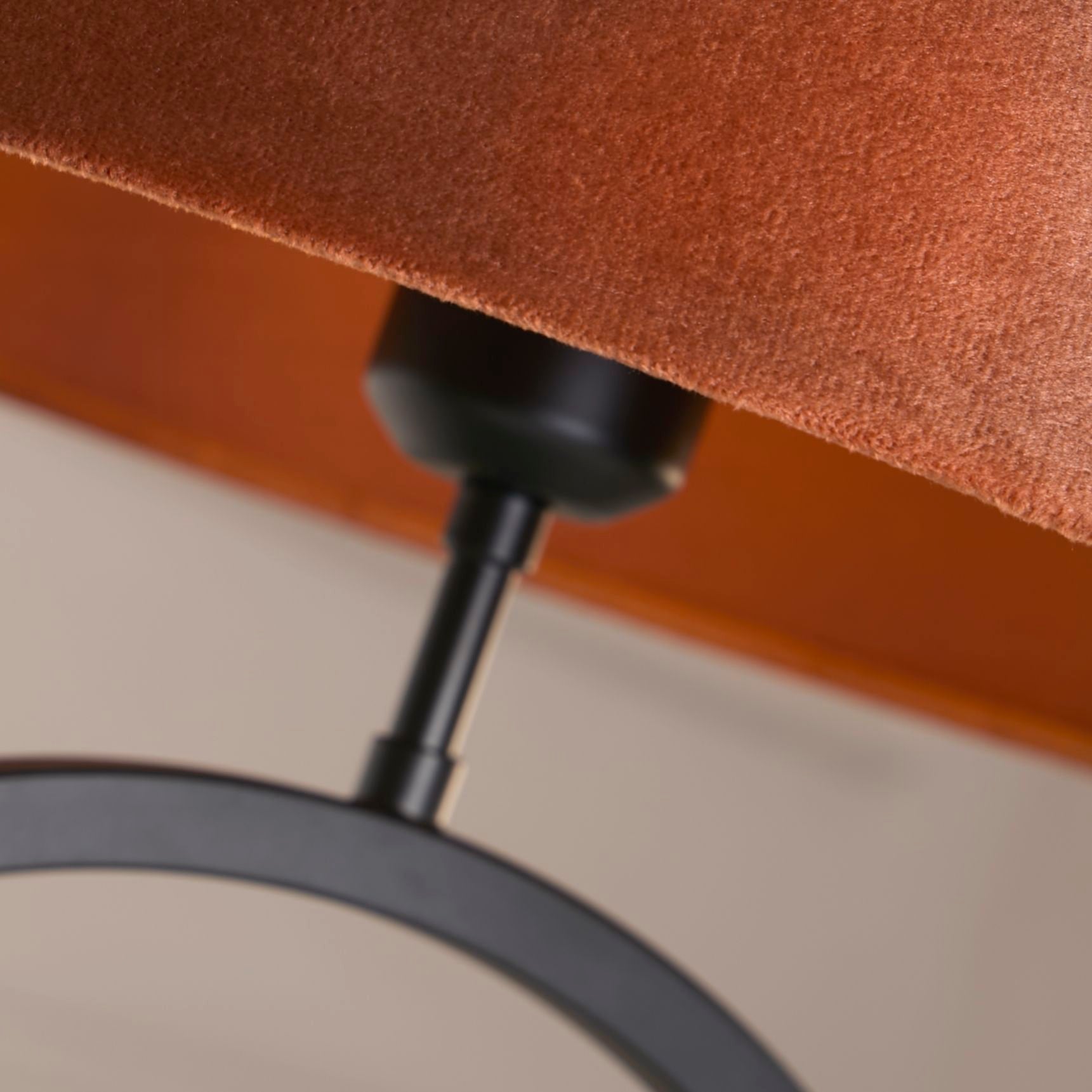 Close up of the black collar joint connecting the burnt orange velvet shade to the matt black ring base
