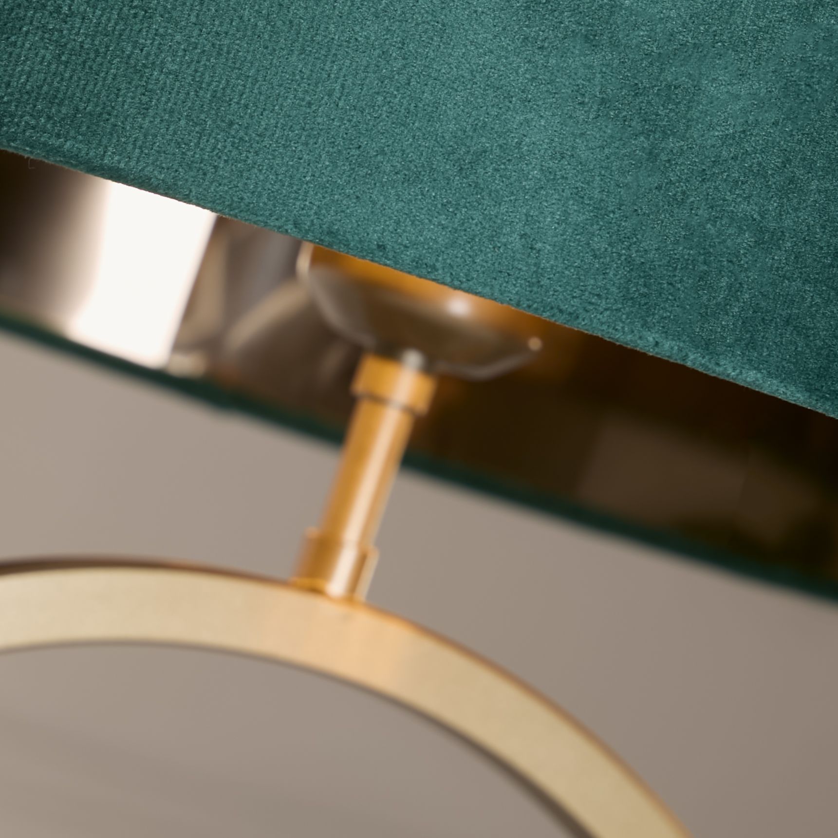 Close up of the bronze ring base and bulb holder beneath the emerald velvet shade, showing the metal finish and velvet texture
