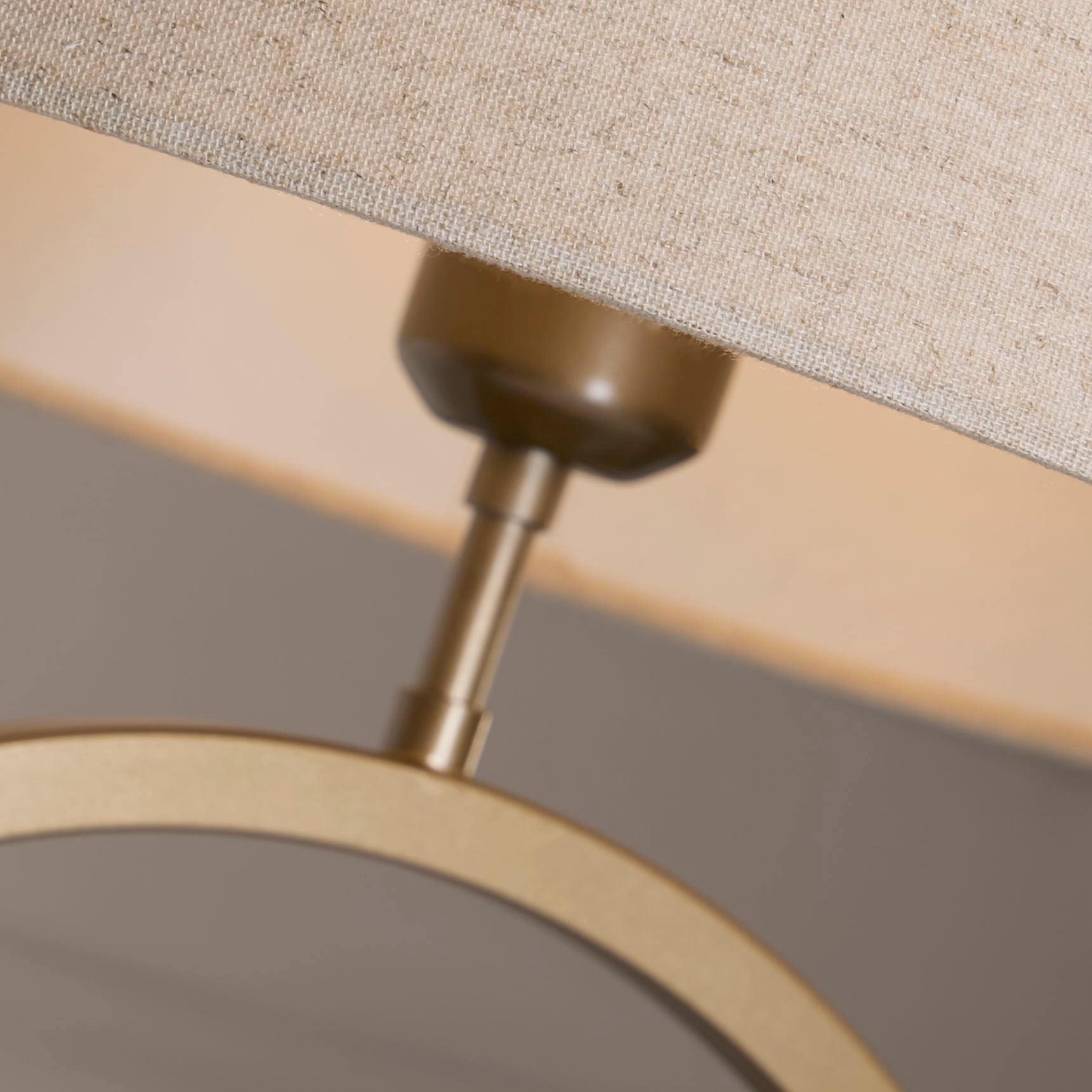 Close up of the bronze ring base and bulb holder beneath the natural linen shade, showing the metal finish and woven linen texture