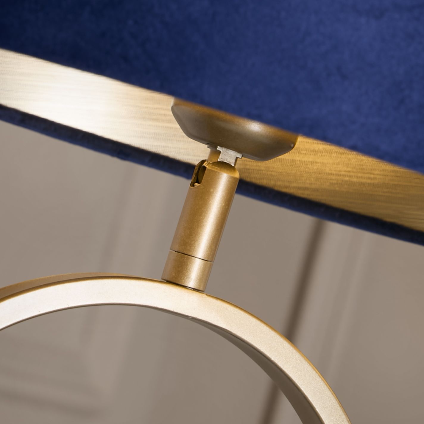 Close up of the brass adjustable joint connecting the navy velvet shade to the bronze oval base