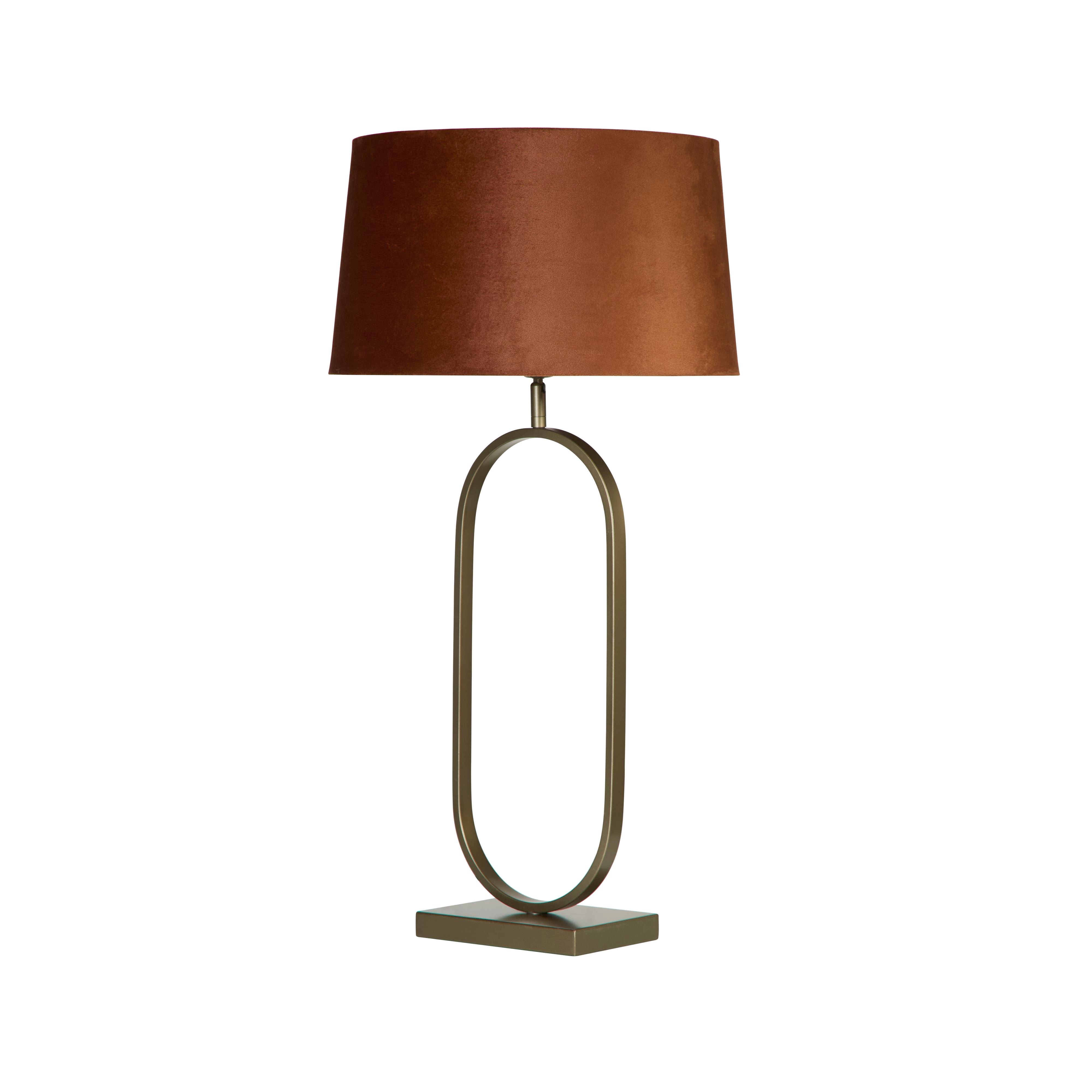 Front view of the bronze oval ring based table lamp with its burnt orange velvet shade, on a plain white studio background