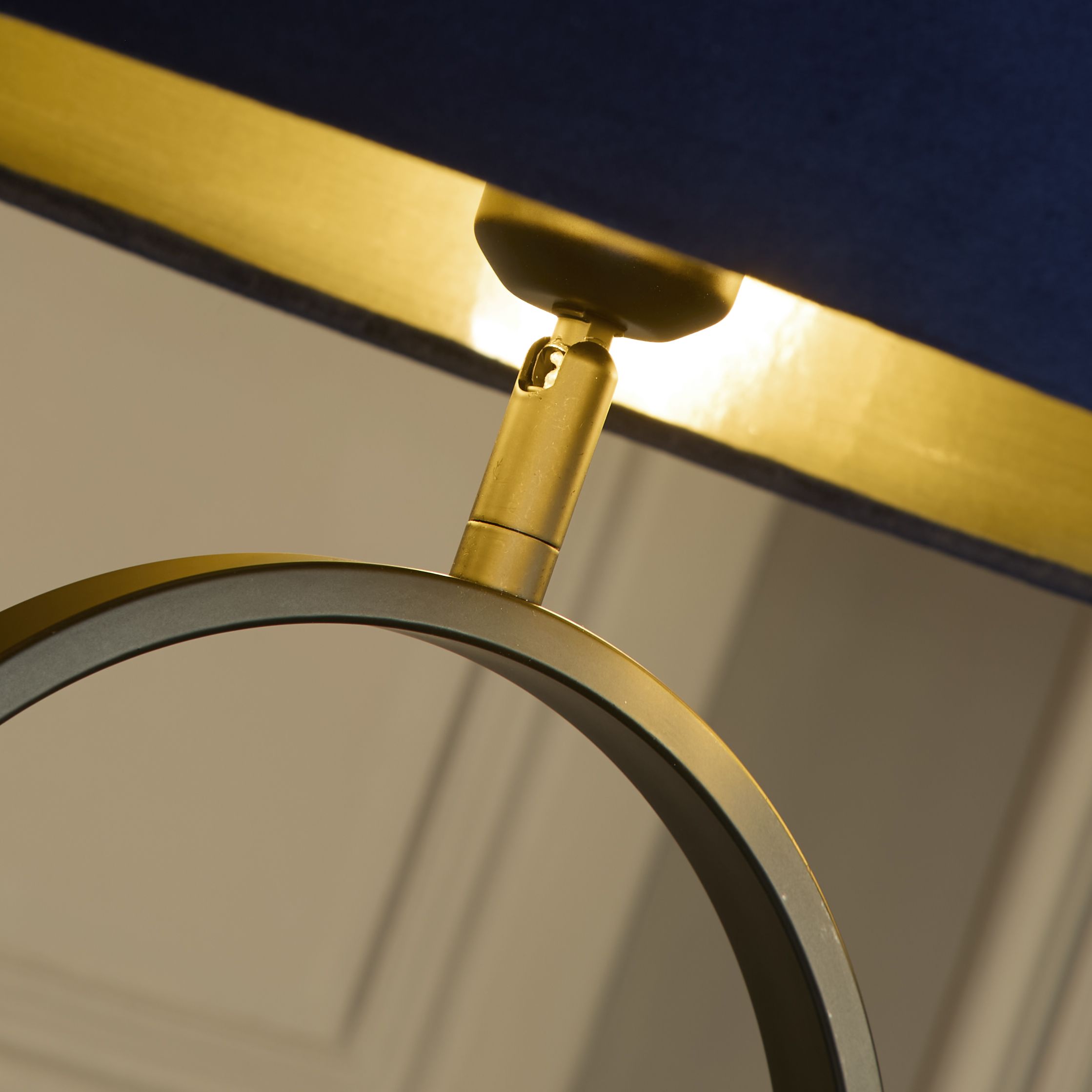 Close up of the brass fitting connecting the navy velvet shade to the black oval frame of the Modish floor lamp