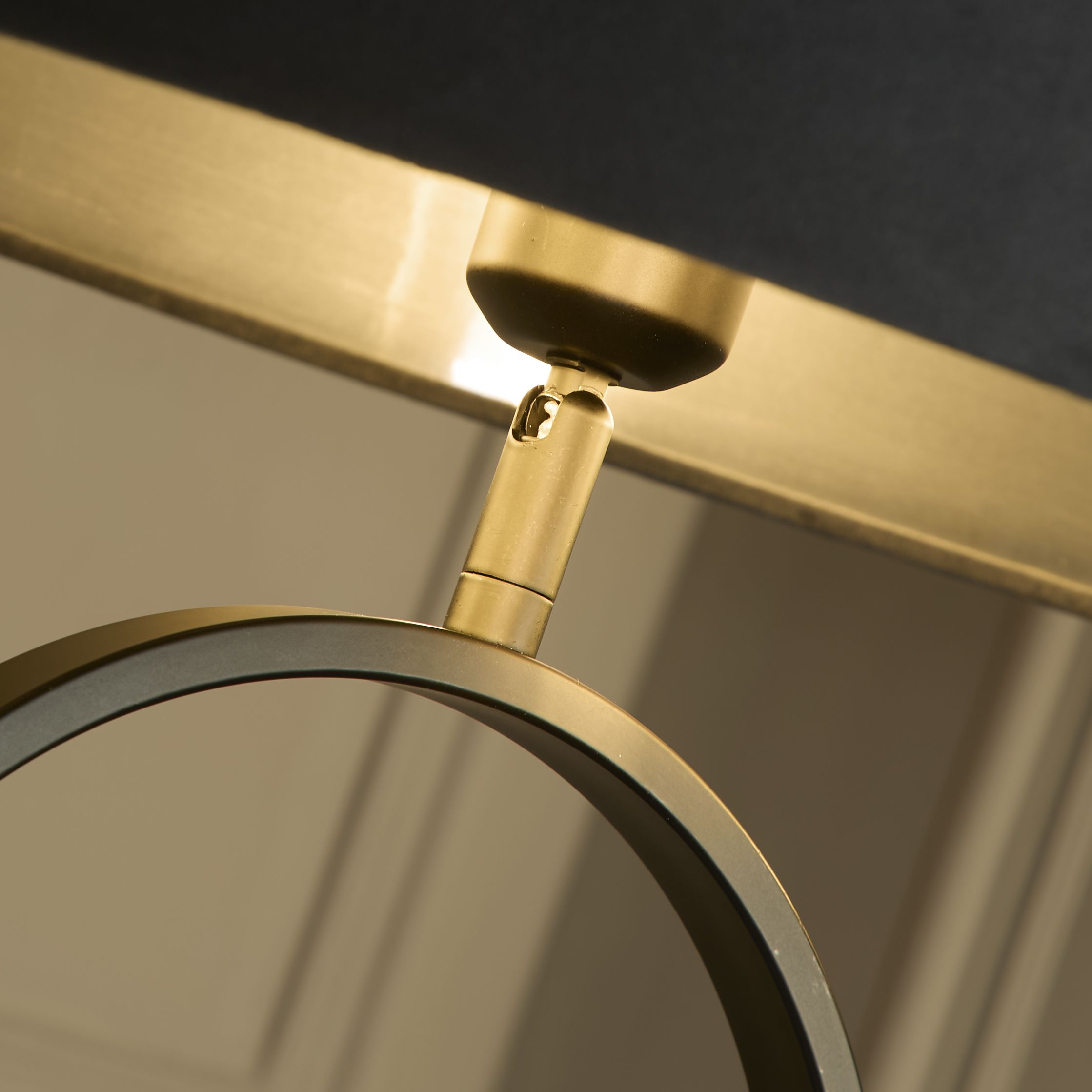 Close up of the brass fitting connecting the dark grey velvet shade to the black oval frame of the Modish floor lamp