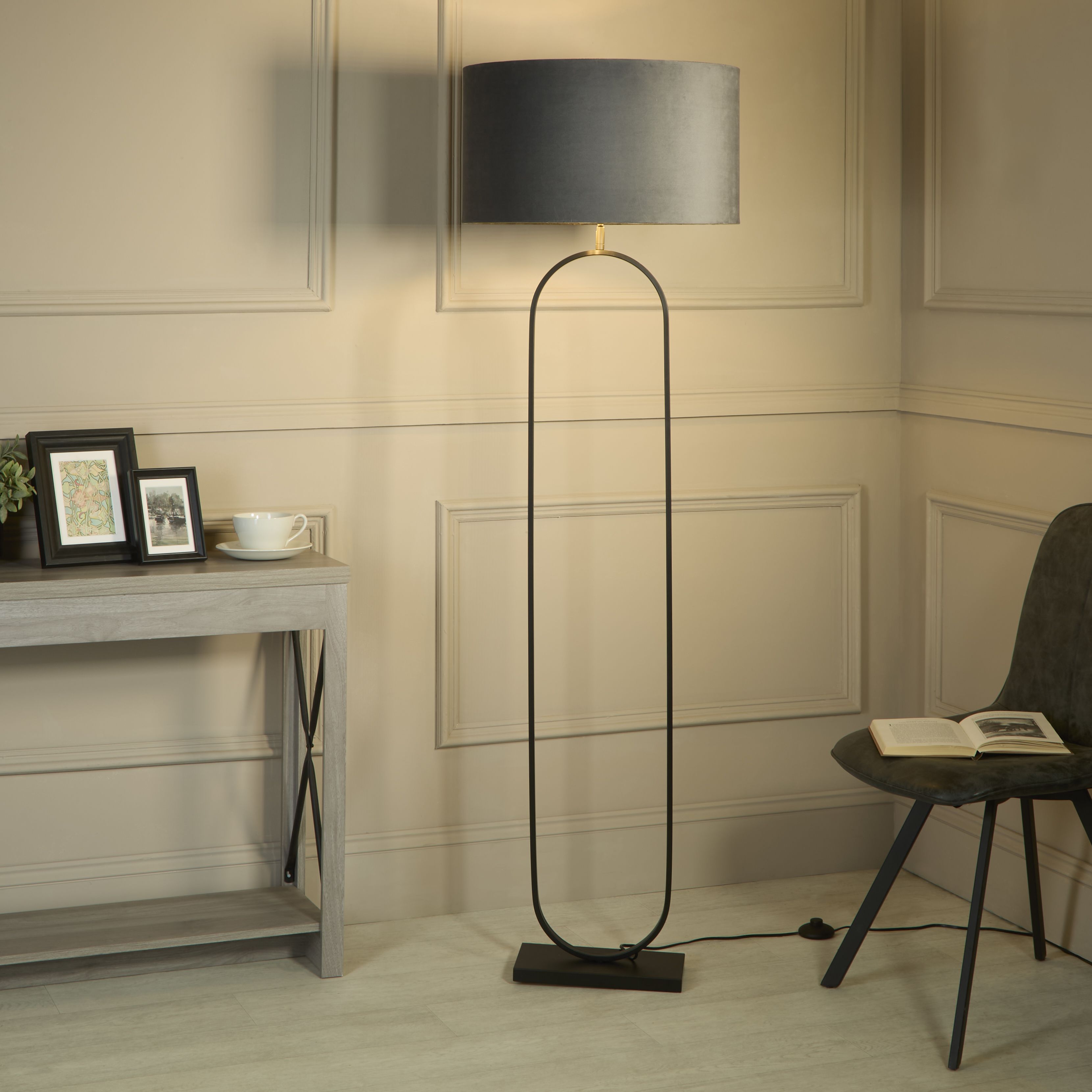 Modish floor lamp with dark grey velvet shade styled in a panelled living room beside a console table and a black armchair