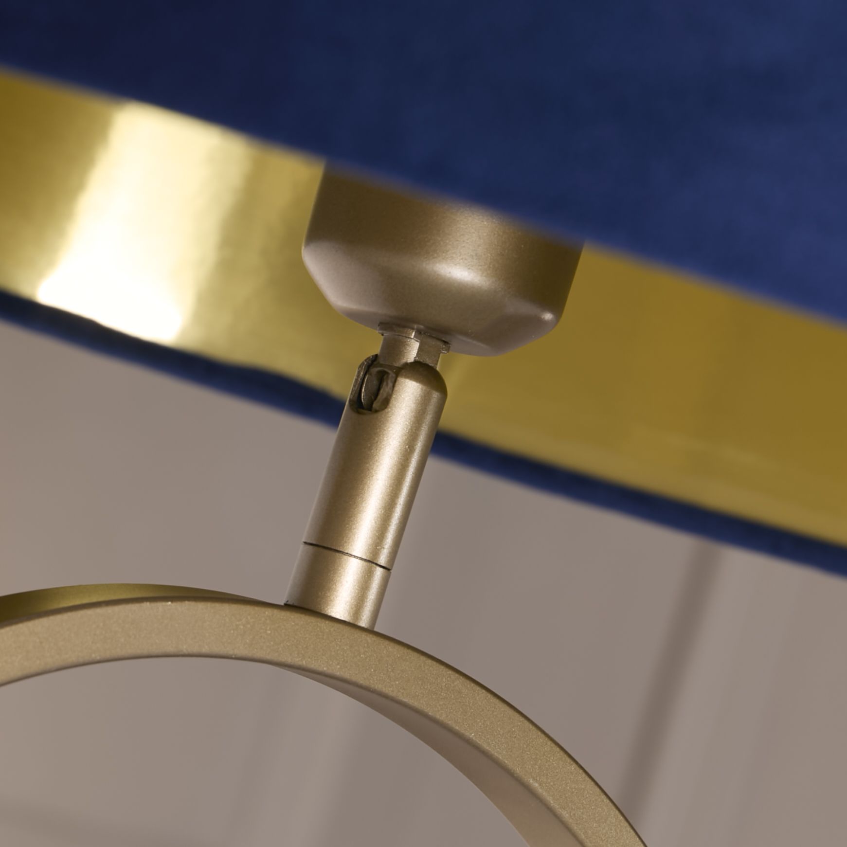 Close up of the bronze oval frame and adjustable fitting where the navy velvet shade attaches, showing the gold interior shade lining