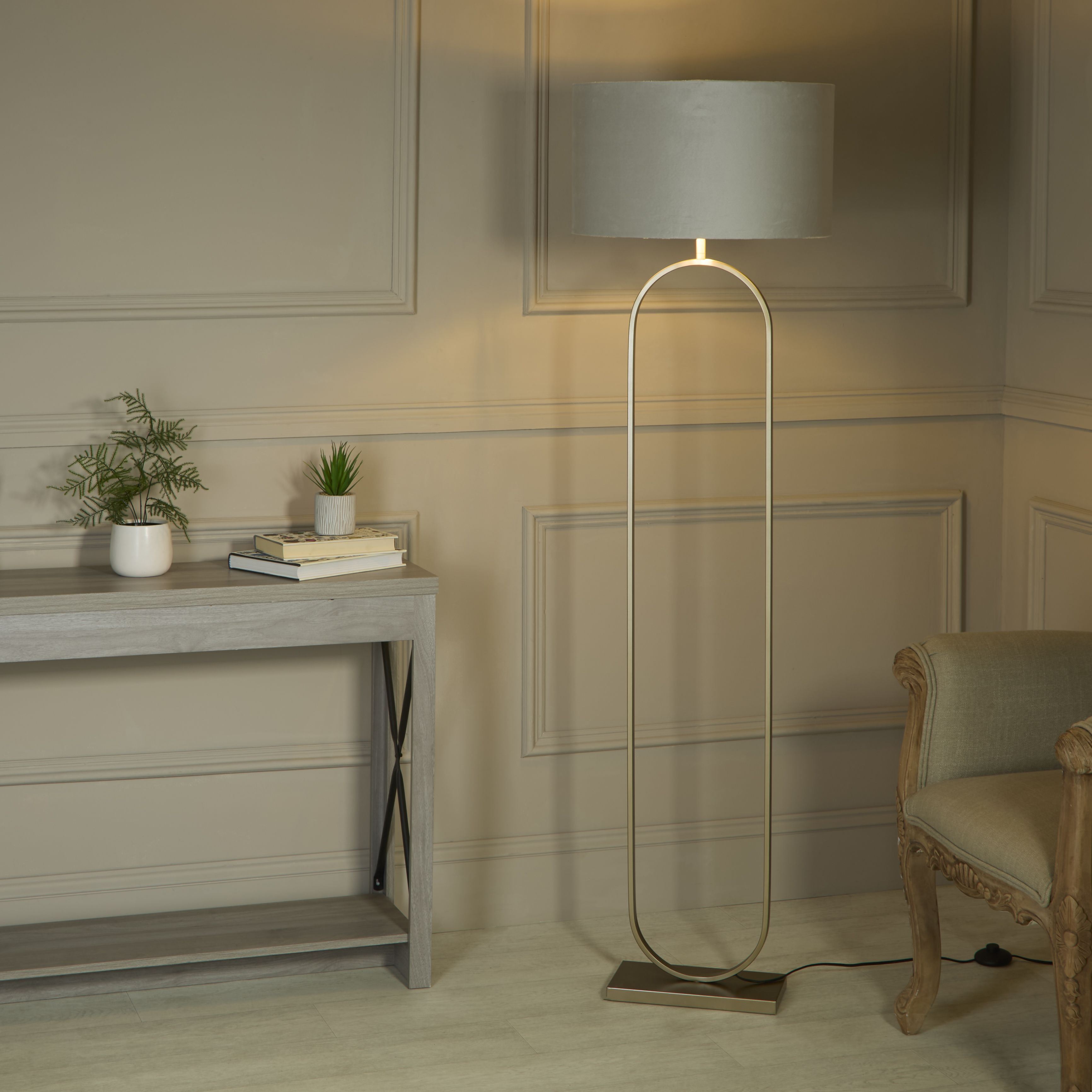 Searchlight Modish floor lamp with light grey velvet shade switched on beside a console table and armchair in a panelled hallway