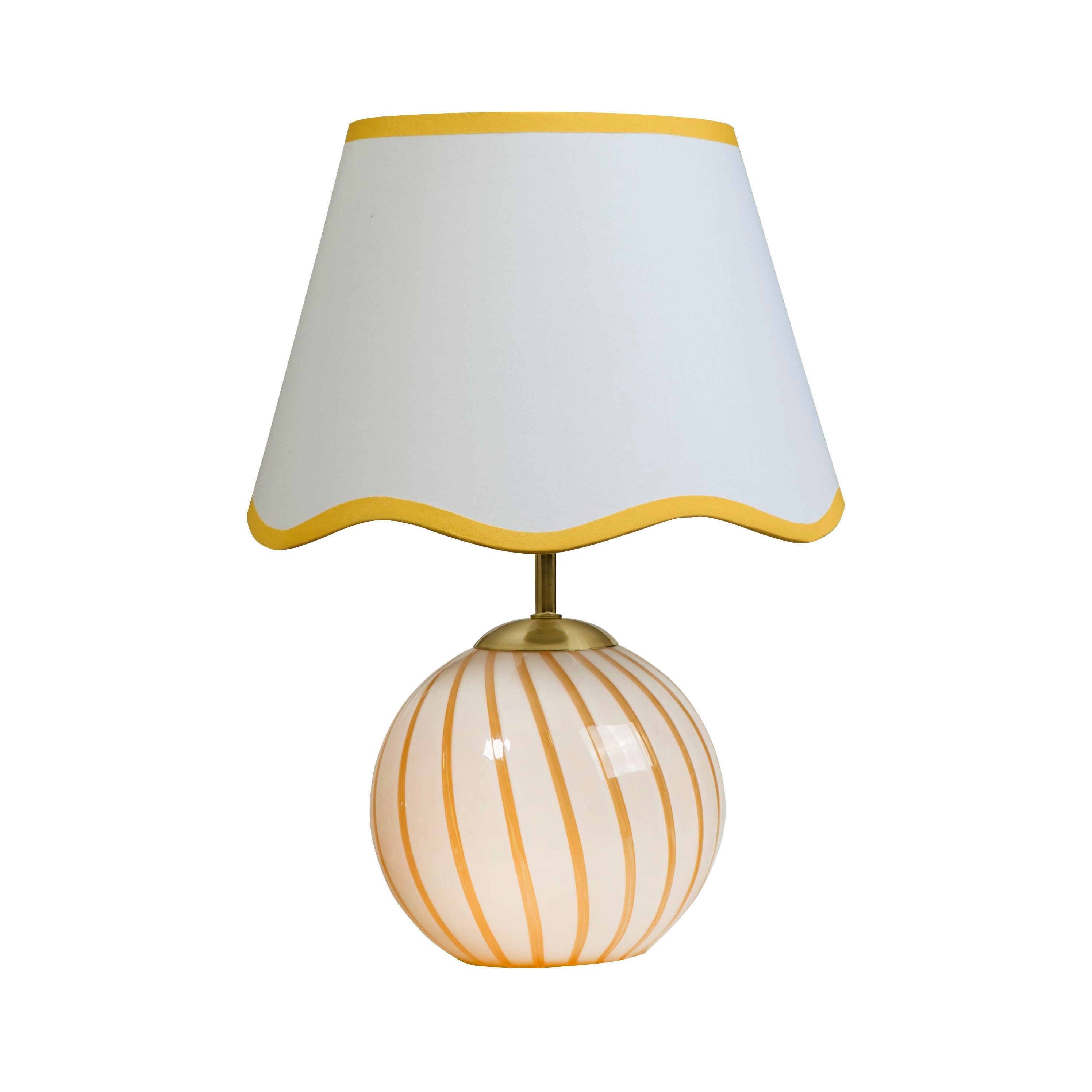 Searchlight Celine table lamp, front view of the striped glass base and scalloped white shade with yellow trim, studio shot on white background