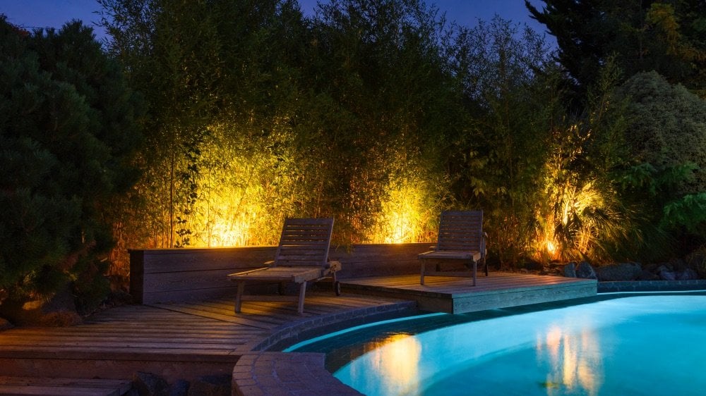 Pool area at night with chairs and illuminated trees