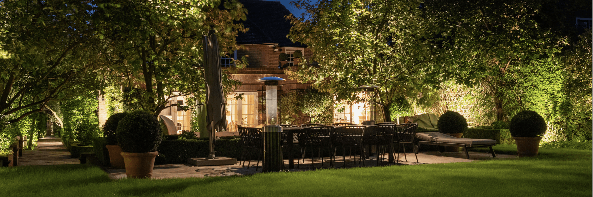 Evening garden scene with seating area and illuminated pathways.