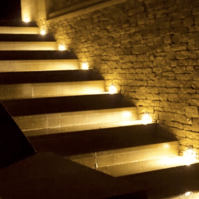 Winding stone staircase with warm lighting against a stone wall.