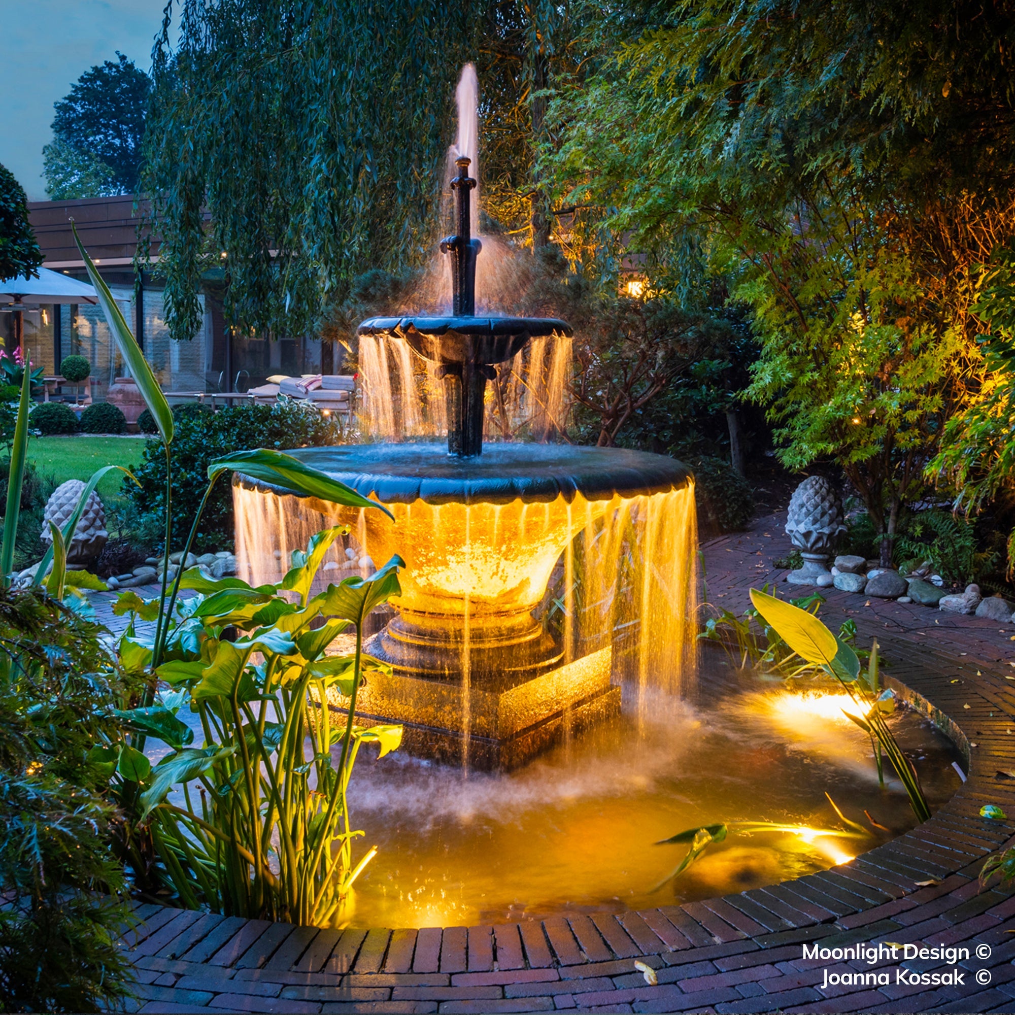 Warm Hunza pond lights illuminate the fountain, aquatic plants and moving water, creating a striking focal point within the garden. A completed Moonlight Design pond lighting project.