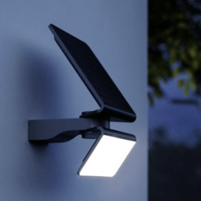 Solar-powered outdoor light fixture on a wall at night.