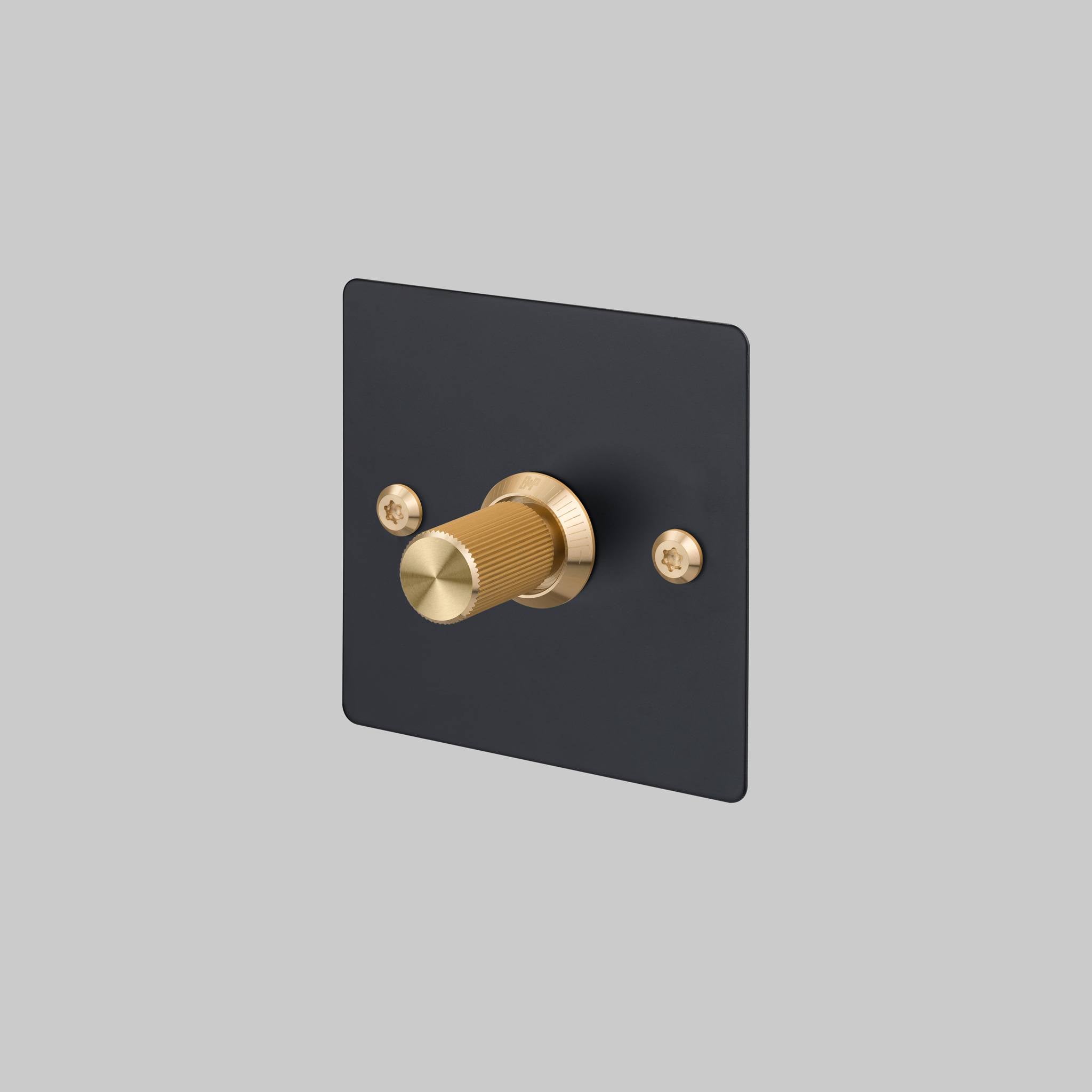 Buster + Punch 1G dimmer switch, black plate with brass linear knurl knob, front view