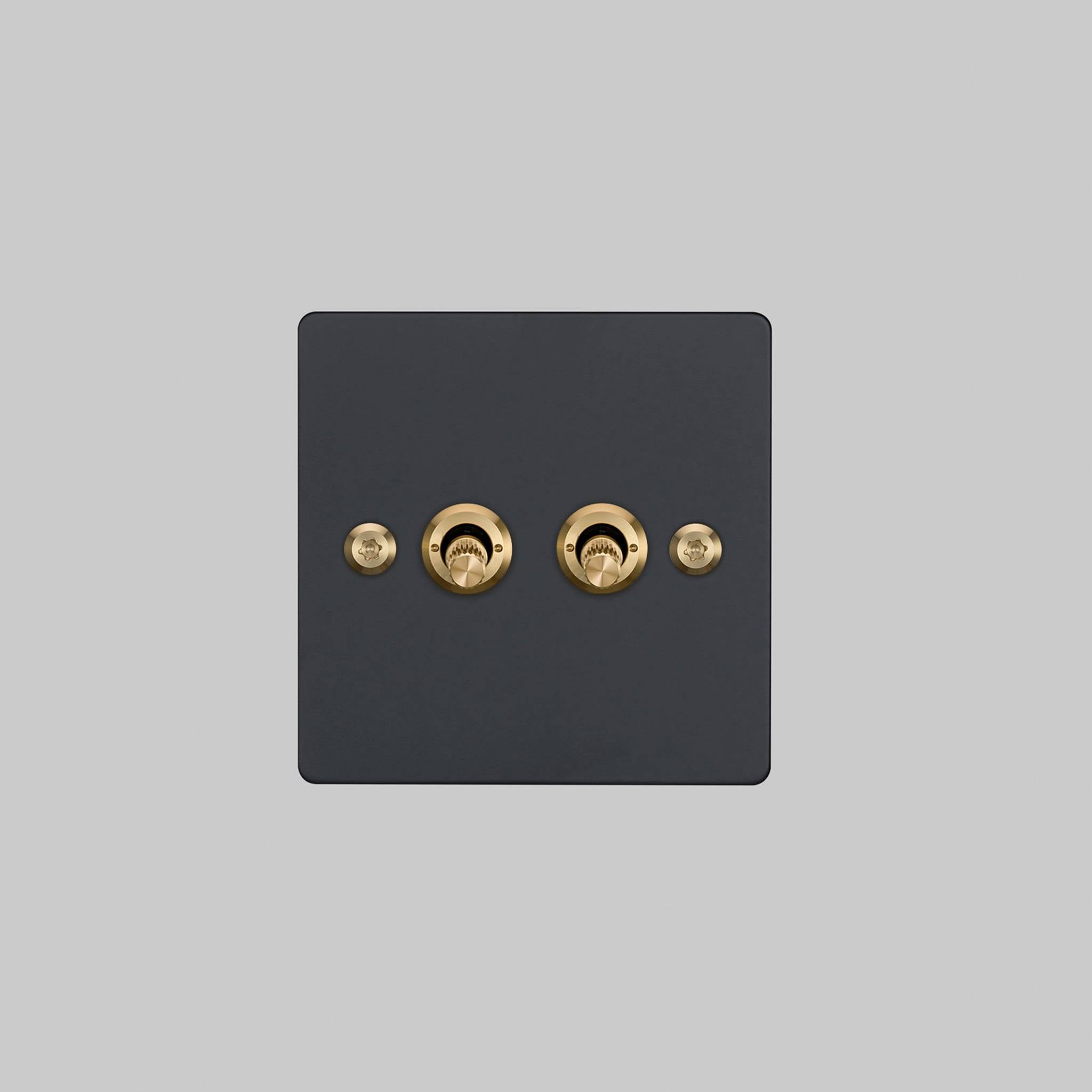 Buster + Punch 2G 2-way toggle switch, black plate with brass linear knurl toggle arm, elevated angle view