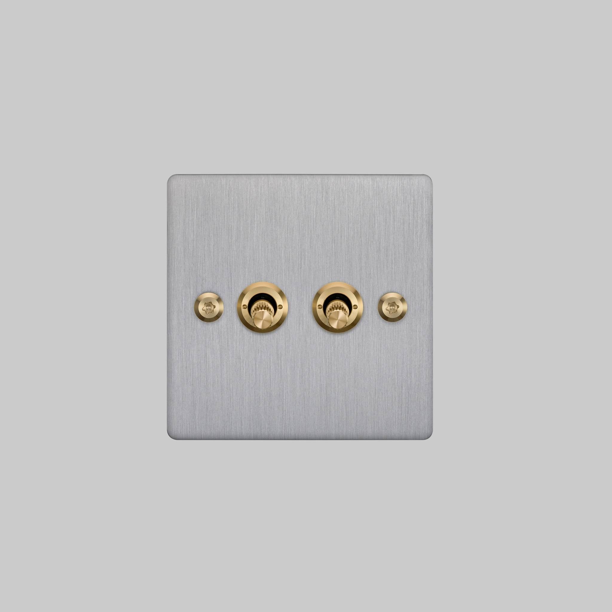 Buster + Punch 2G 2-way toggle switch, steel plate with brass linear knurl toggle arm, elevated angle view