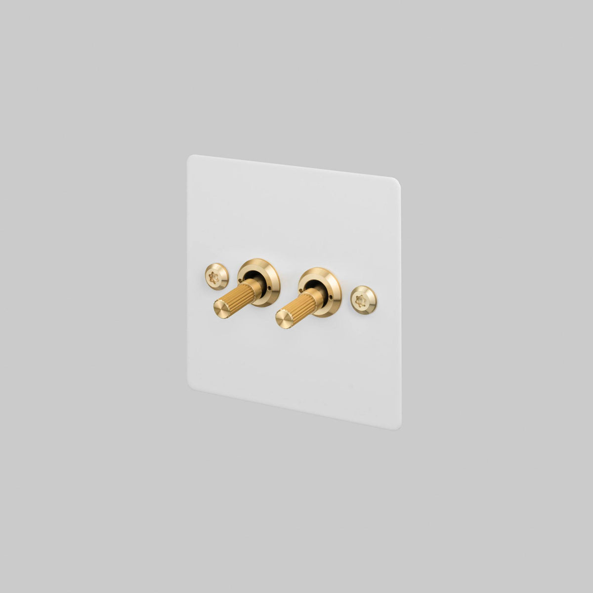 Buster + Punch 2G toggle switch, white plate with brass linear knurl toggle arms, front view