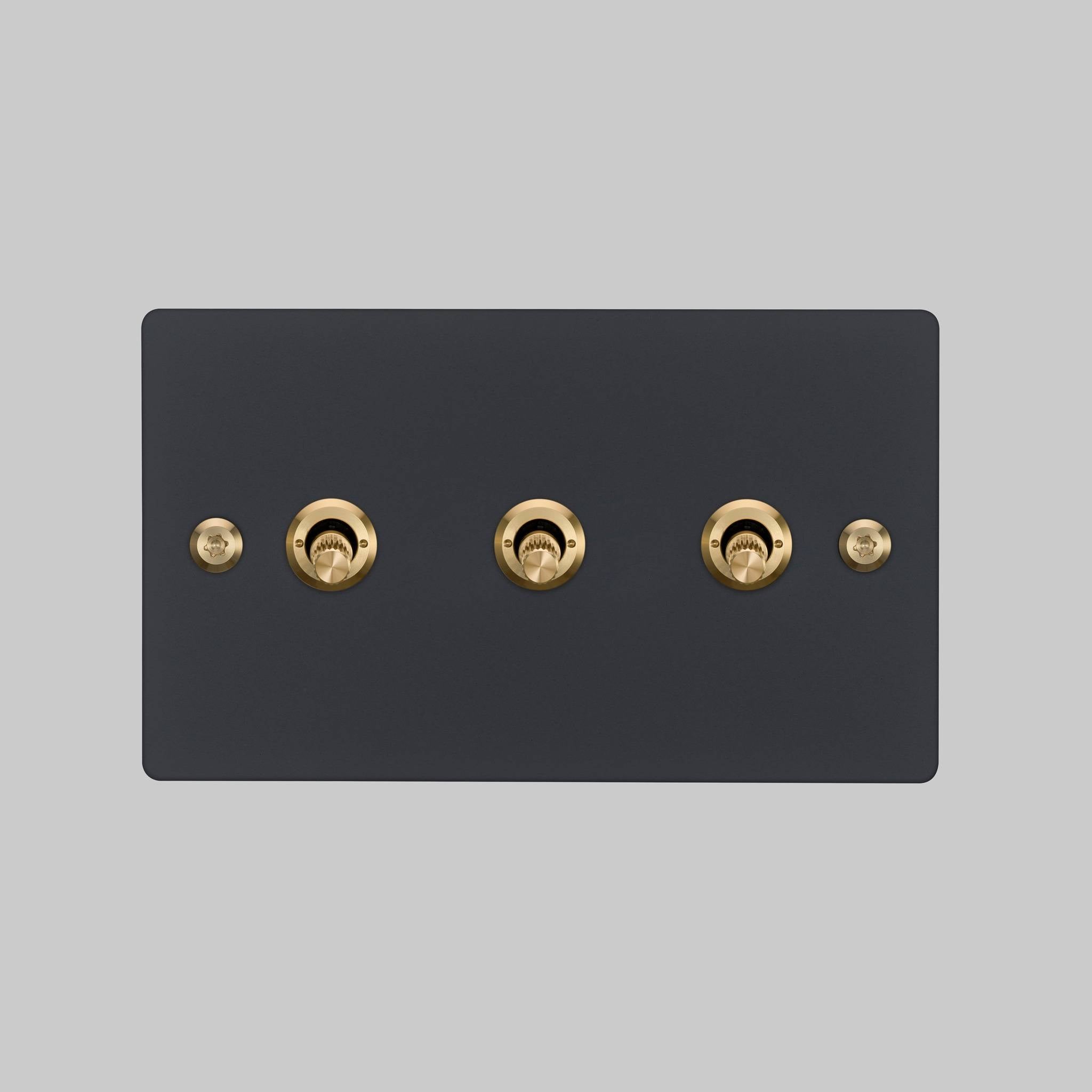 Buster + Punch 3G toggle switch, Black plate with Brass linear knurl toggle arm, front elevation view