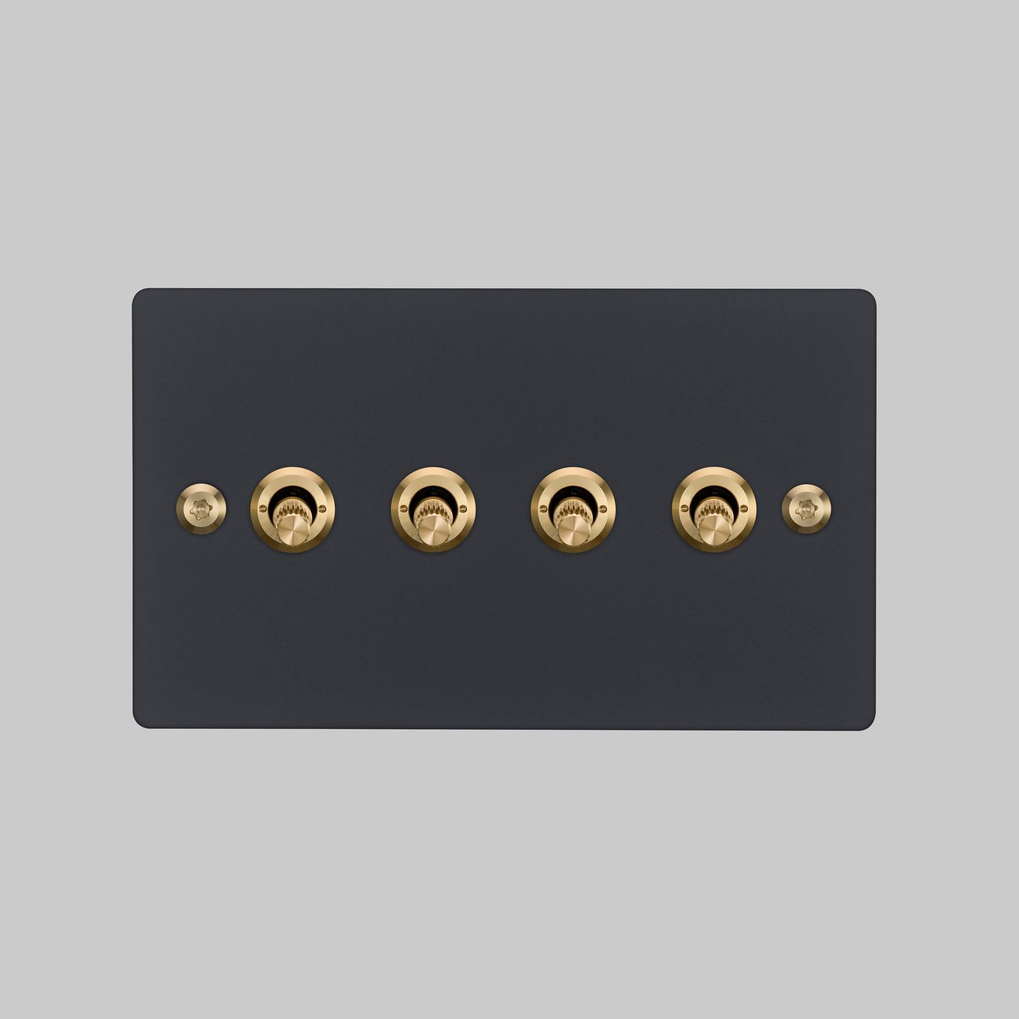 Buster + Punch 4G toggle switch, black plate with brass linear knurl toggle arms, elevated angle view
