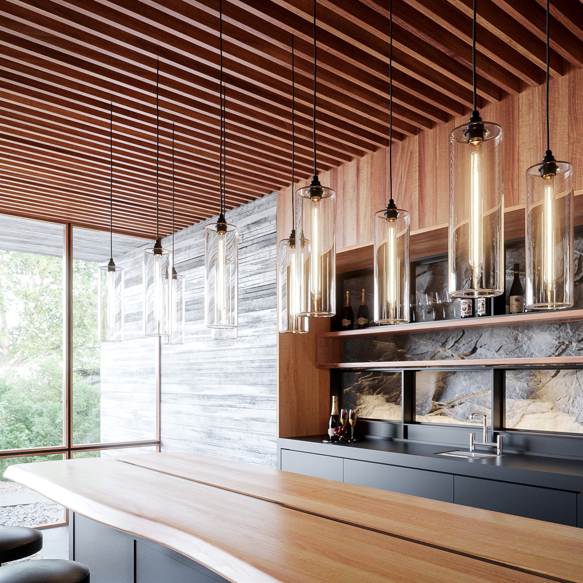 Row of clear glass cylinder pendants on dark flex hanging at different heights above a timber bar counter, with a slatted timber ceiling and a tall window behind