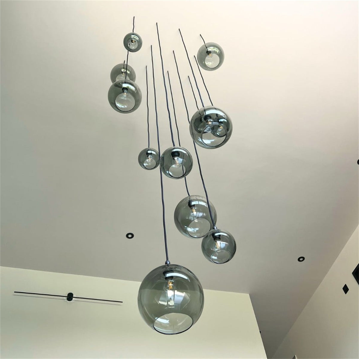 Leverint Pimlico cascade cluster of smoky grey glass globe pendants of different sizes hanging at varied heights below a high white ceiling