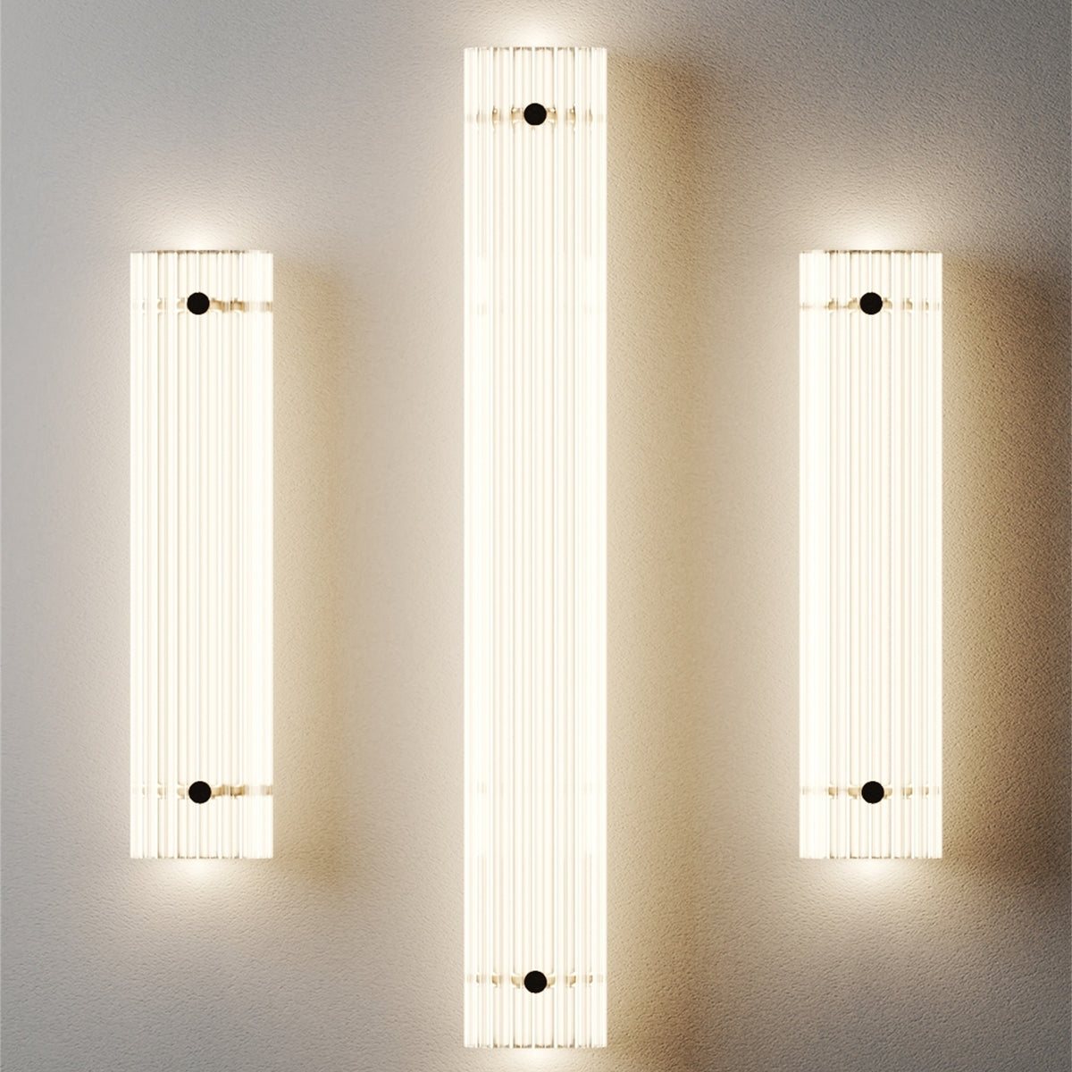 Three lit Leverint Temple Pillar Lights on a grey wall, a taller one between two shorter ones, ribbed glass columns glowing