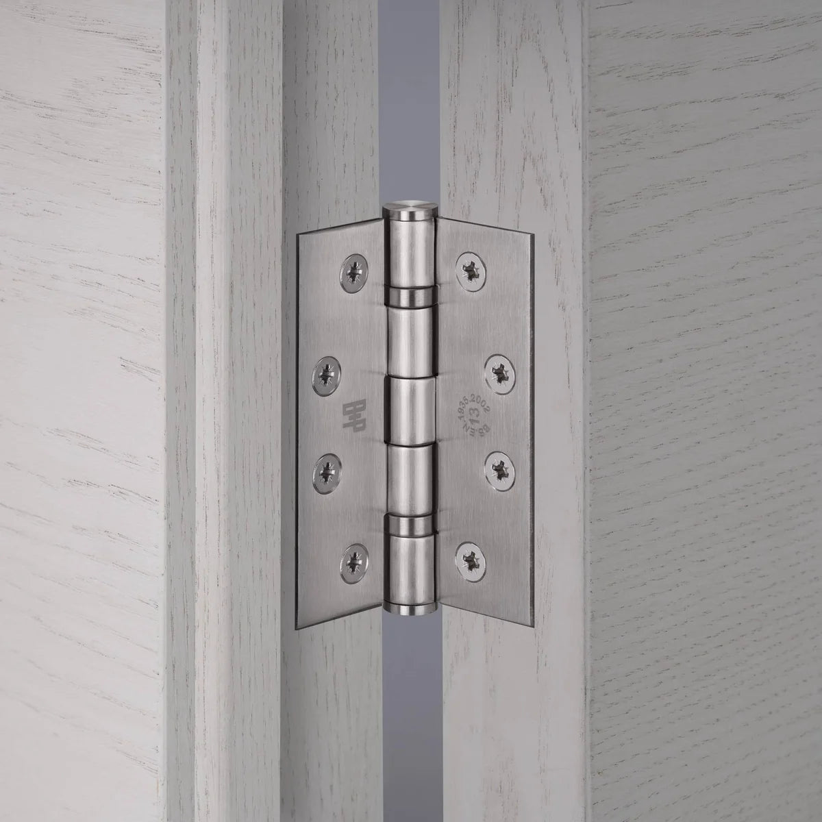 Buster + Punch steel door hinge fitted between a pale grey oak door and frame, with cross head screws