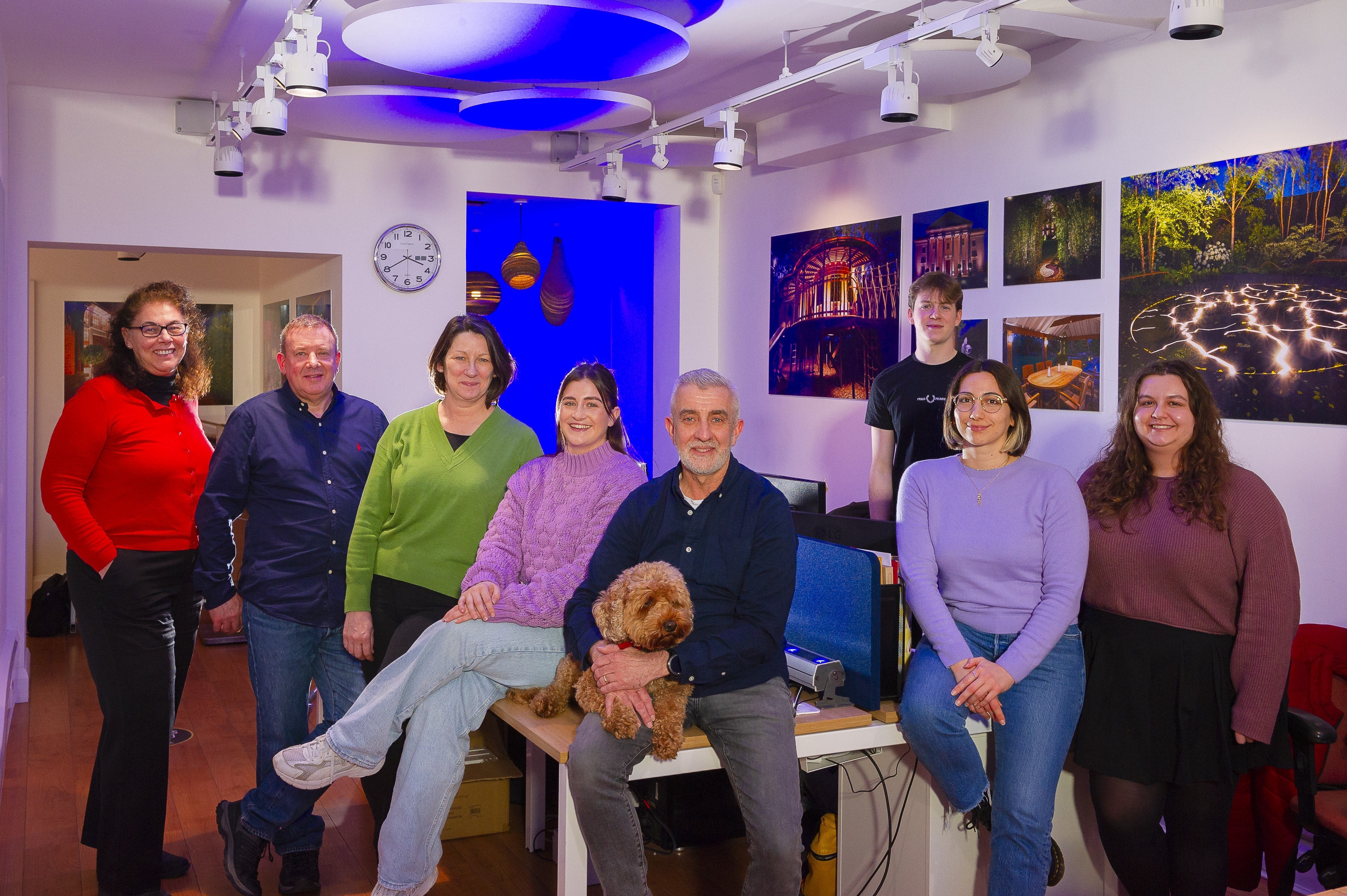 Group of people in a modern office setting, posing for a photo.