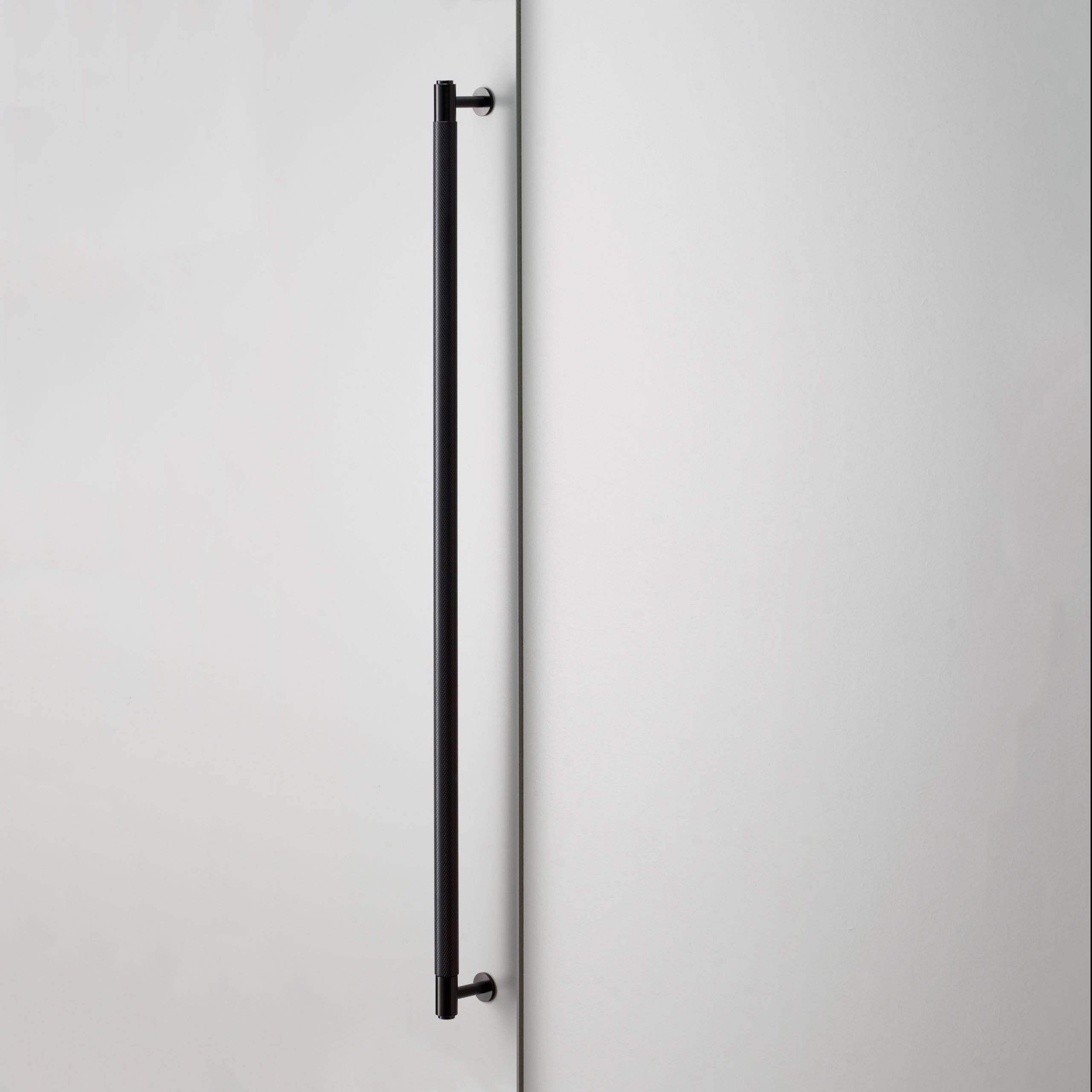 Buster + Punch Closet Bar in Cross Knurl Black mounted vertically on a wardrobe door
