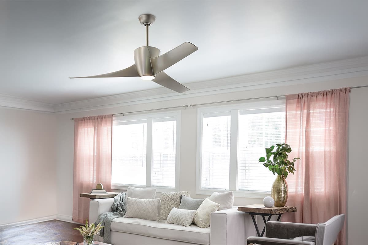 Kichler Phree brushed nickel ceiling fan with integrated LED light, in a bright living room with blush pink curtains