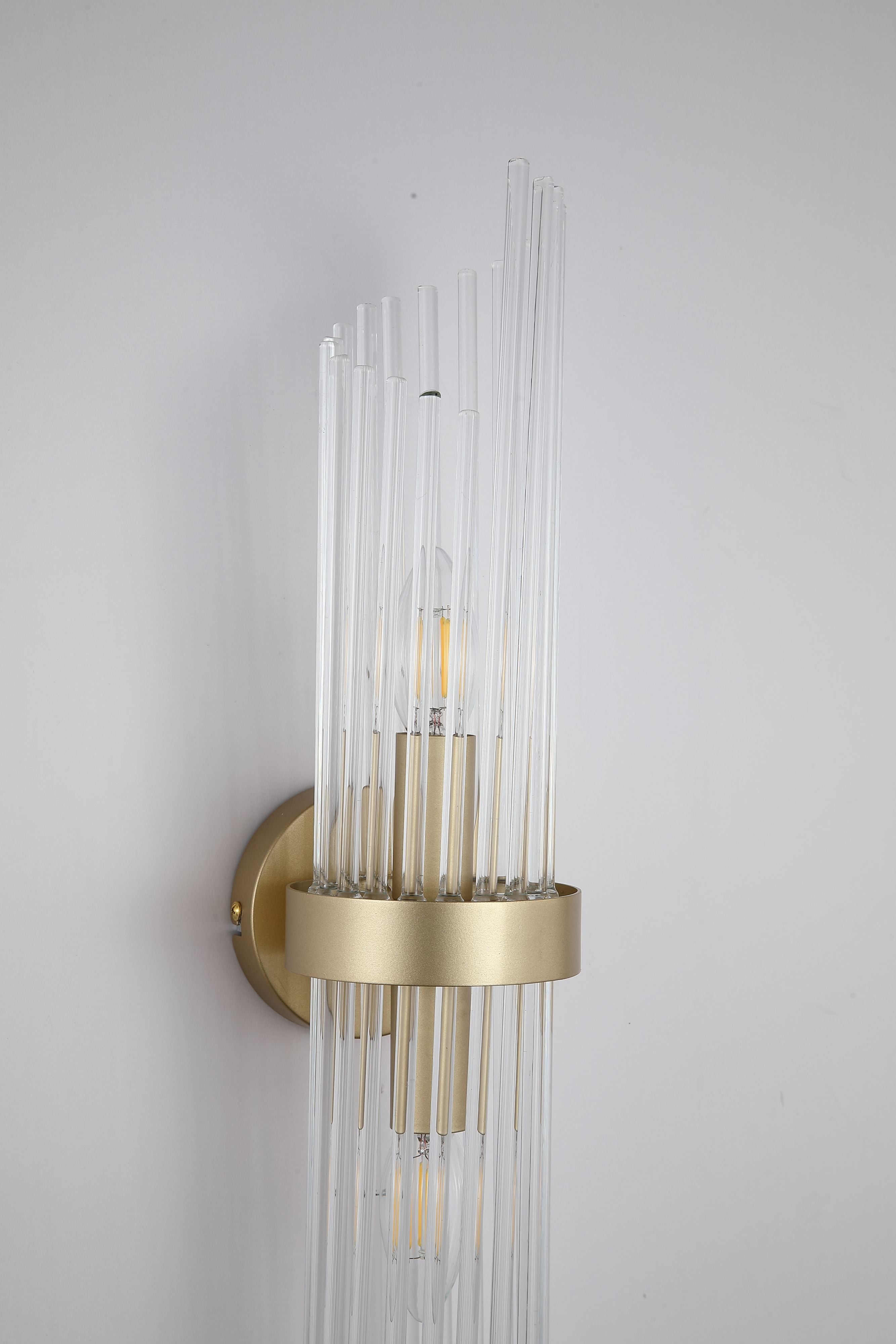 Close up of the Searchlight Lara wall light, showing the gold band and clear glass rods surrounding a lit candle bulb
