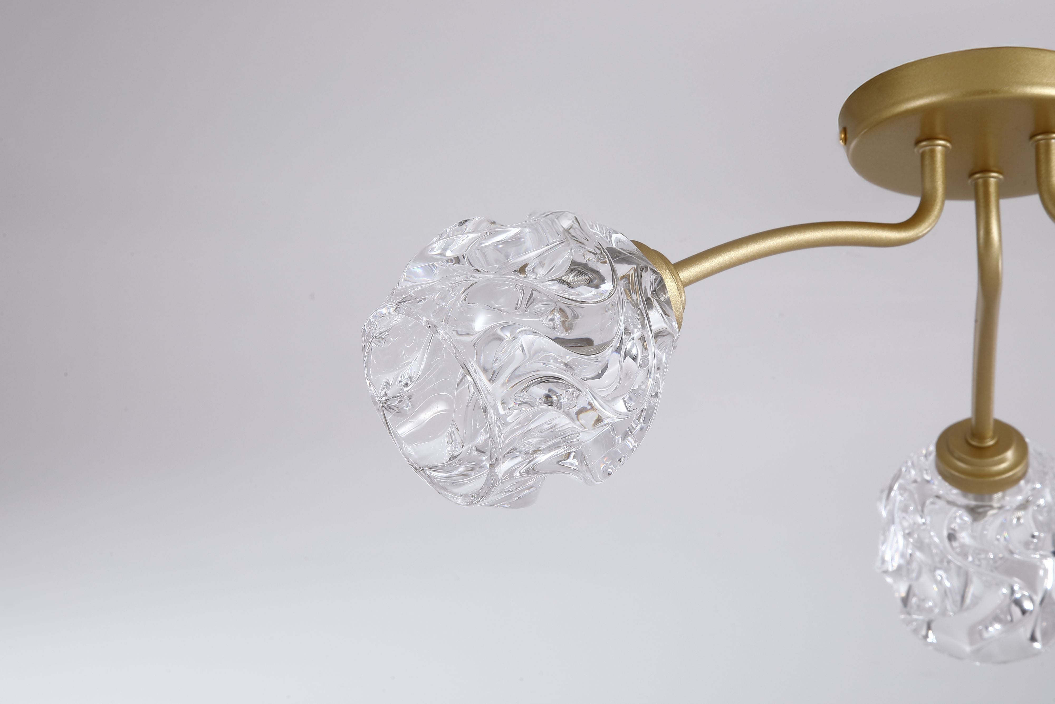 Close up of a crumpled clear glass shade on the Searchlight Astral 3 light flush ceiling light in soft gold, showing the textured glass detail