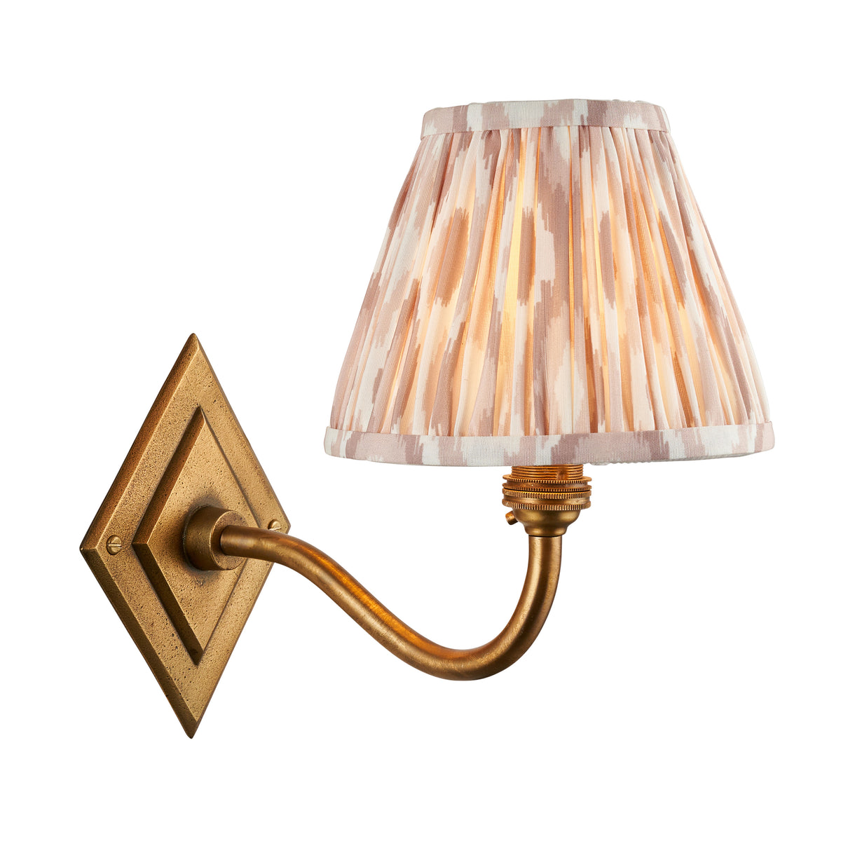 Endon Diamond Curve wall light in antique brass with lit 16cm pleated ikat shade in blush pink and white, cut out on white