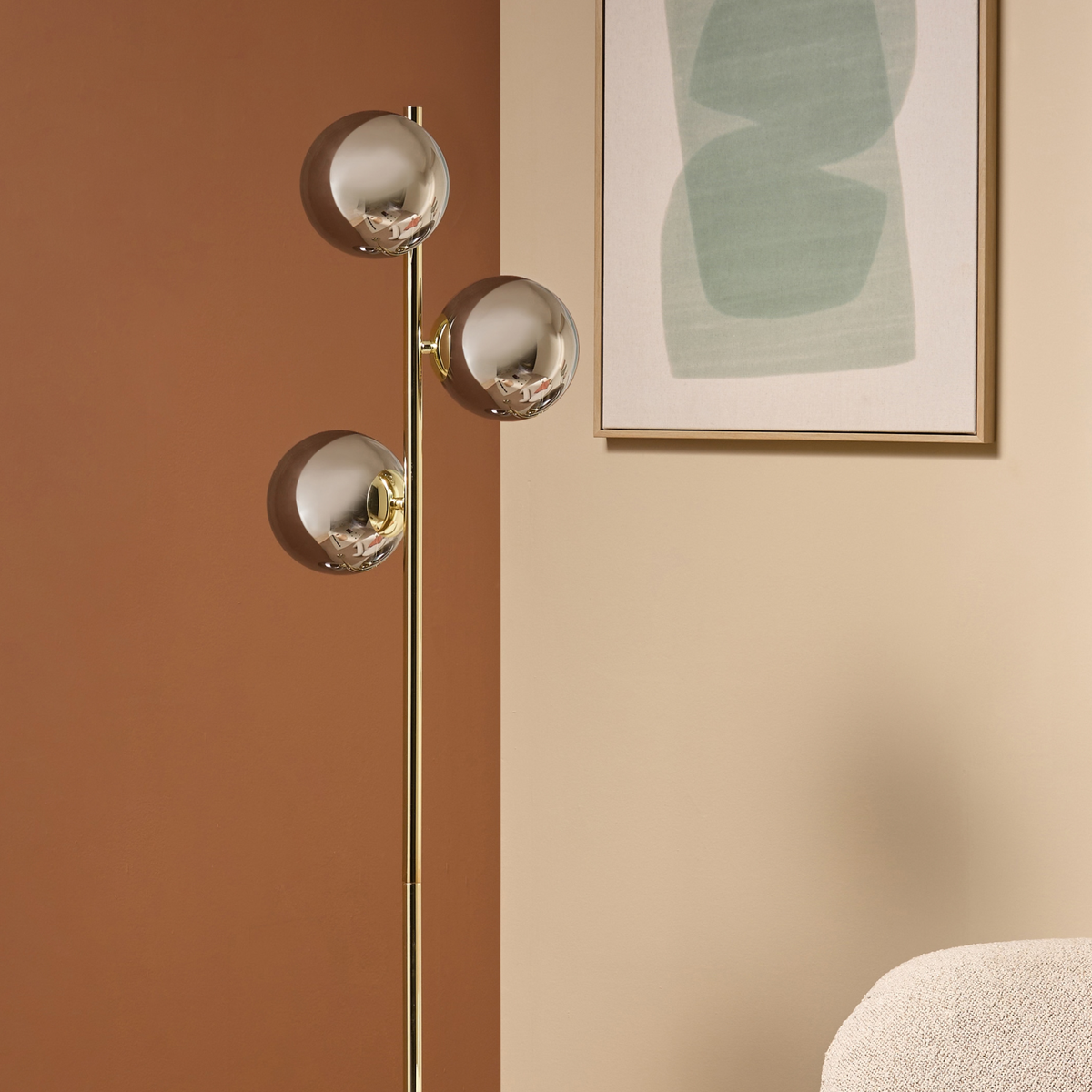 MADE Globe floor lamp in polished brass with three lustre glass globes, close lifestyle shot with wall art