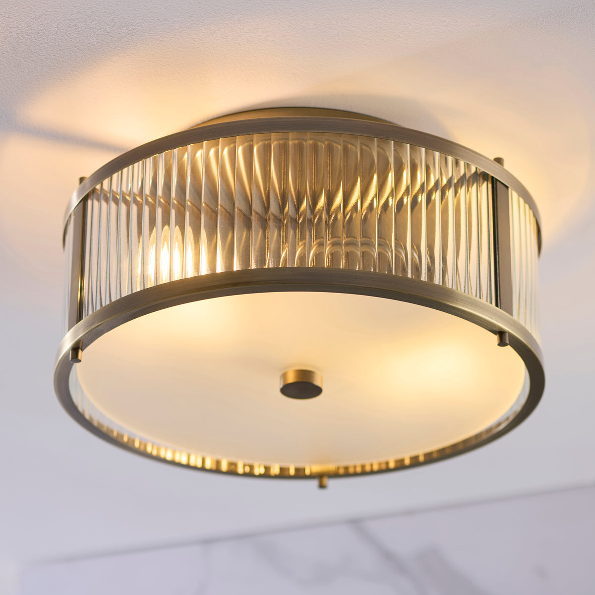 Detail shot of the clear ribbed glass panels on the Endon Ridgeton IP44 flush ceiling light in antique brass showing the frosted glass diffuser below